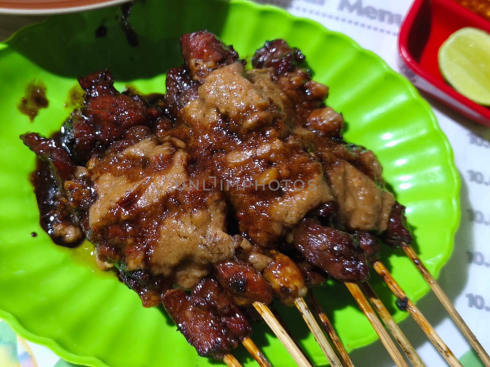 A plate of succulent-looking Sate Kambing or goat satay with peanut sauce, ready to be devoured. This is from Indonesia.