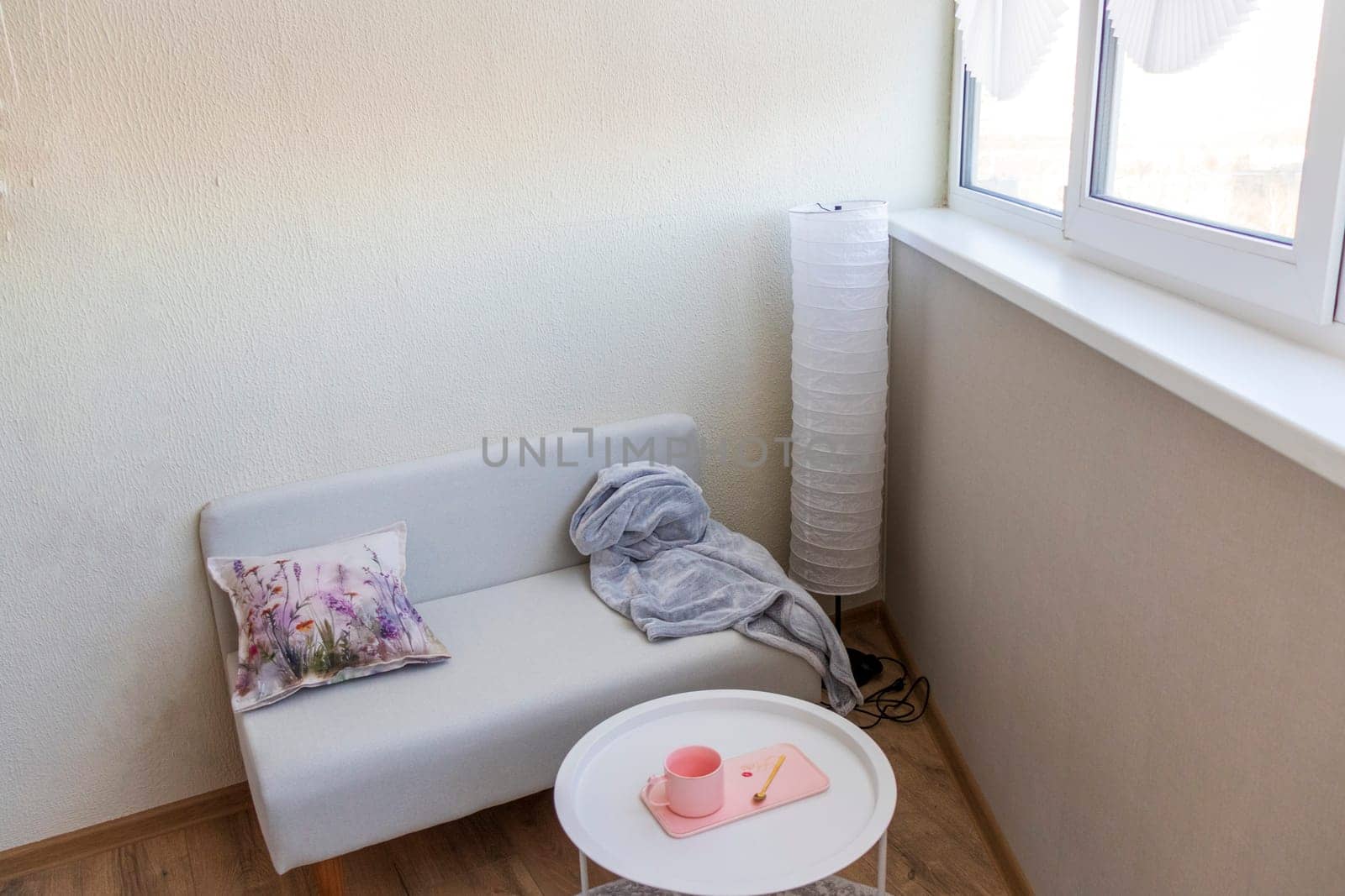 Interior of the balcony of the modern apartment. Sofa, coffee table, standing light