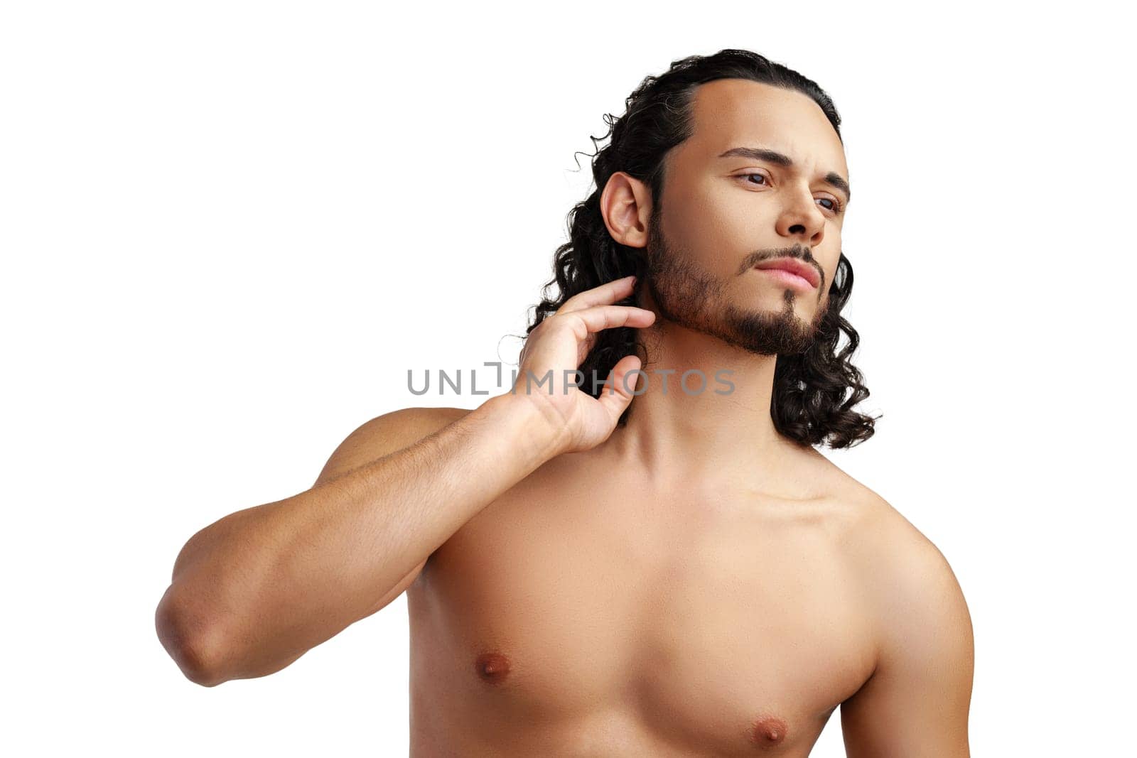Young man with curly hair thoughtfully posing against a plain background in a studio setting