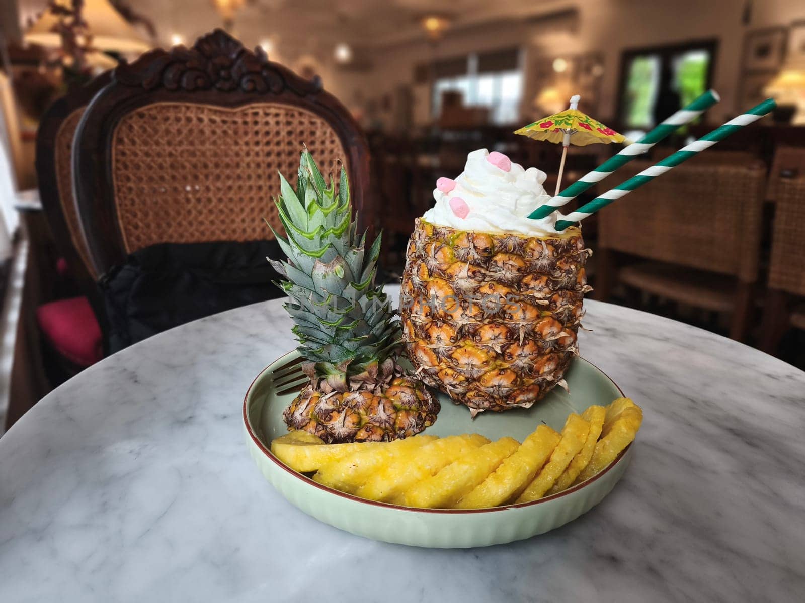 A refreshing pineapple cocktail served in a hollowed out pineapple, topped with whipped cream and a colorful umbrella. A Pinacolada
