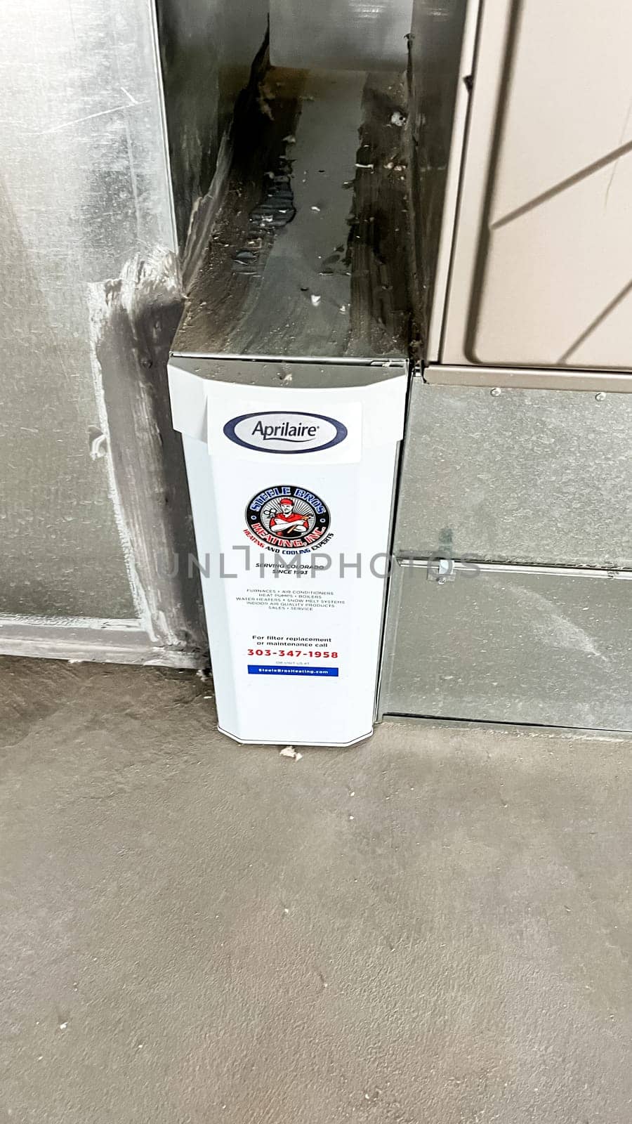 Parker, Colorado, USA-January 11, 2023-Close-up view of an Aprilaire air filtration unit installed alongside the HVAC furnace in the basement of a newly constructed residential home. The system is designed to improve indoor air quality by filtering dust, allergens, and other particles.