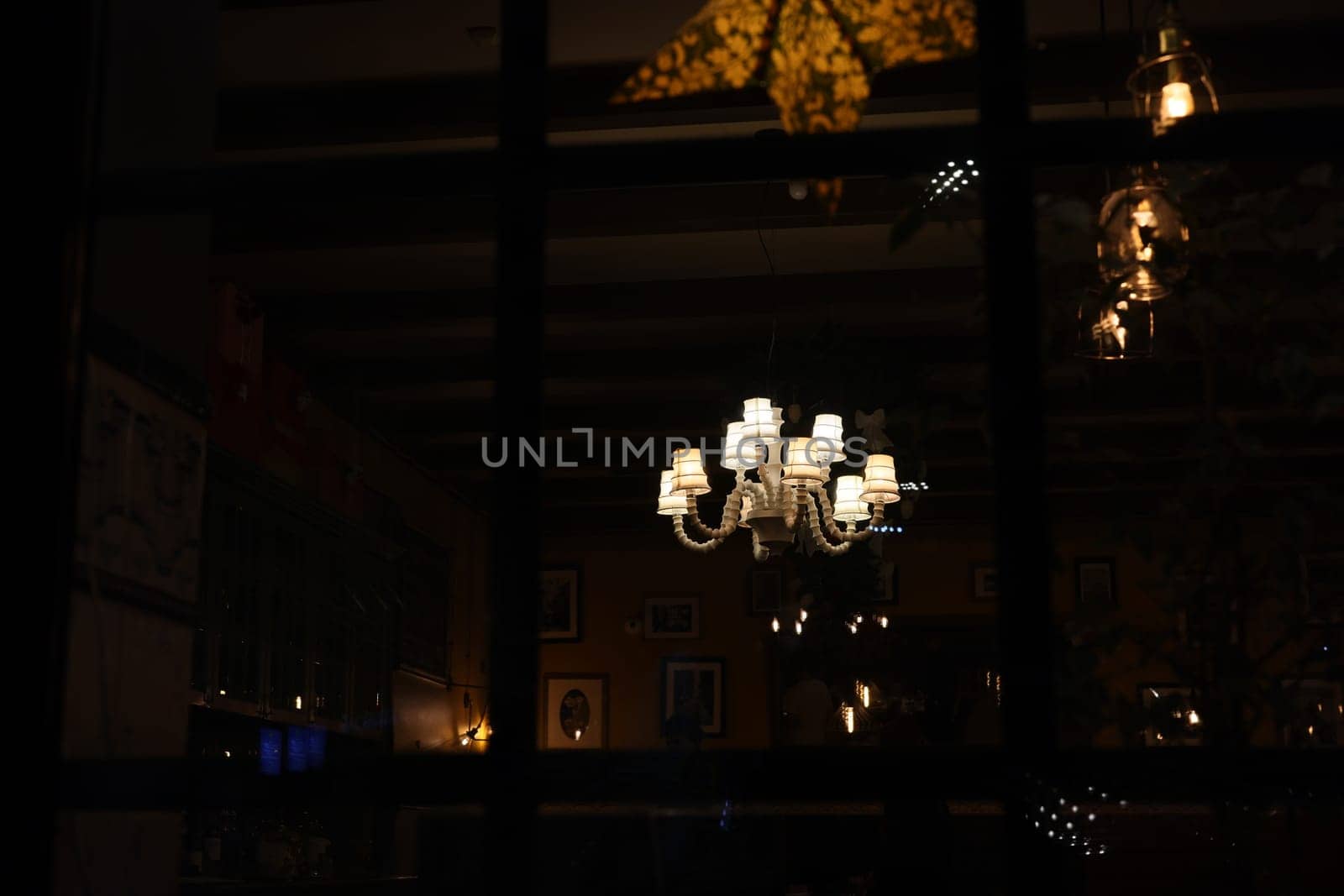 A stunning chandelier casts warm light in a cozy restaurant setting, creating an inviting atmosphere.