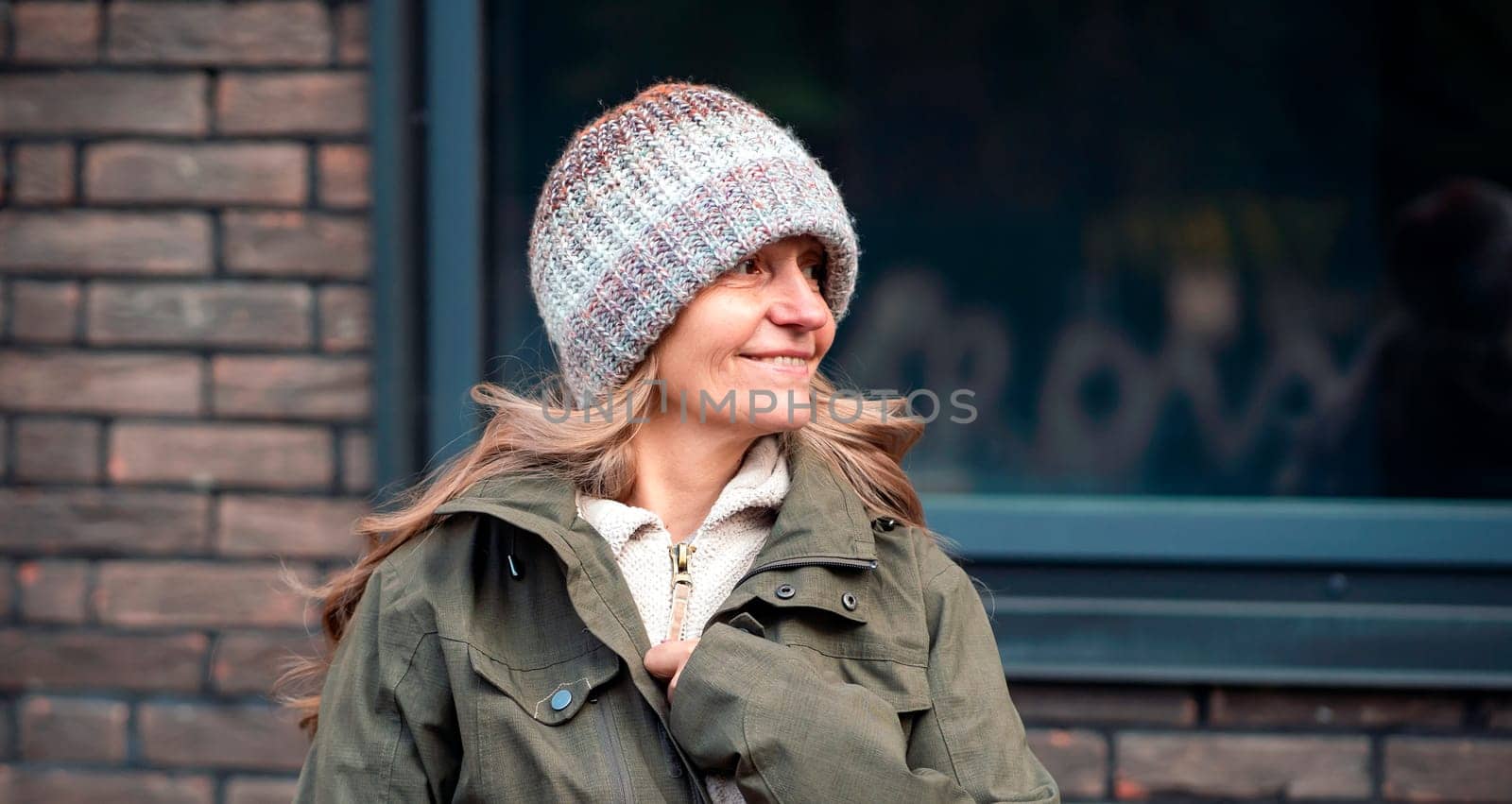 An elderly 60 beautiful woman with a kind smile is walking outdoors on a sunny autumn day, a happy old lady, a grandmother takes care of her appearance, natural beauty with wrinkles portrait closeup.