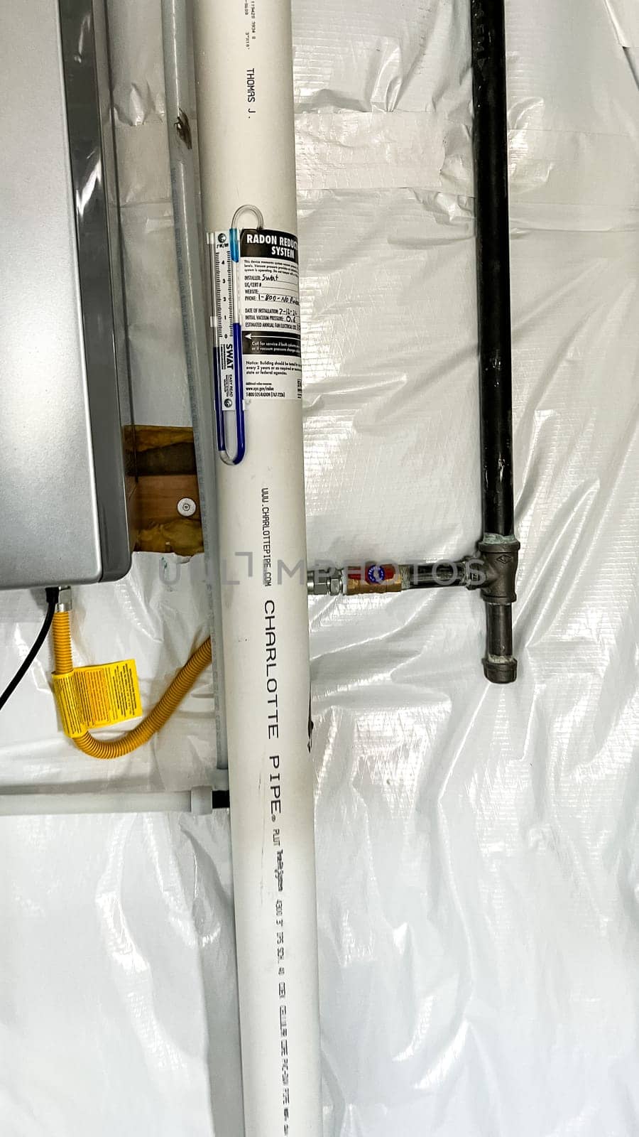 Parker, Colorado, USA-January 11, 2023-A close-up view of a radon reduction system installed in the basement of a newly constructed residential home. The system features a labeled pipe with installation details and a manometer to monitor air pressure, ensuring safe indoor air quality.