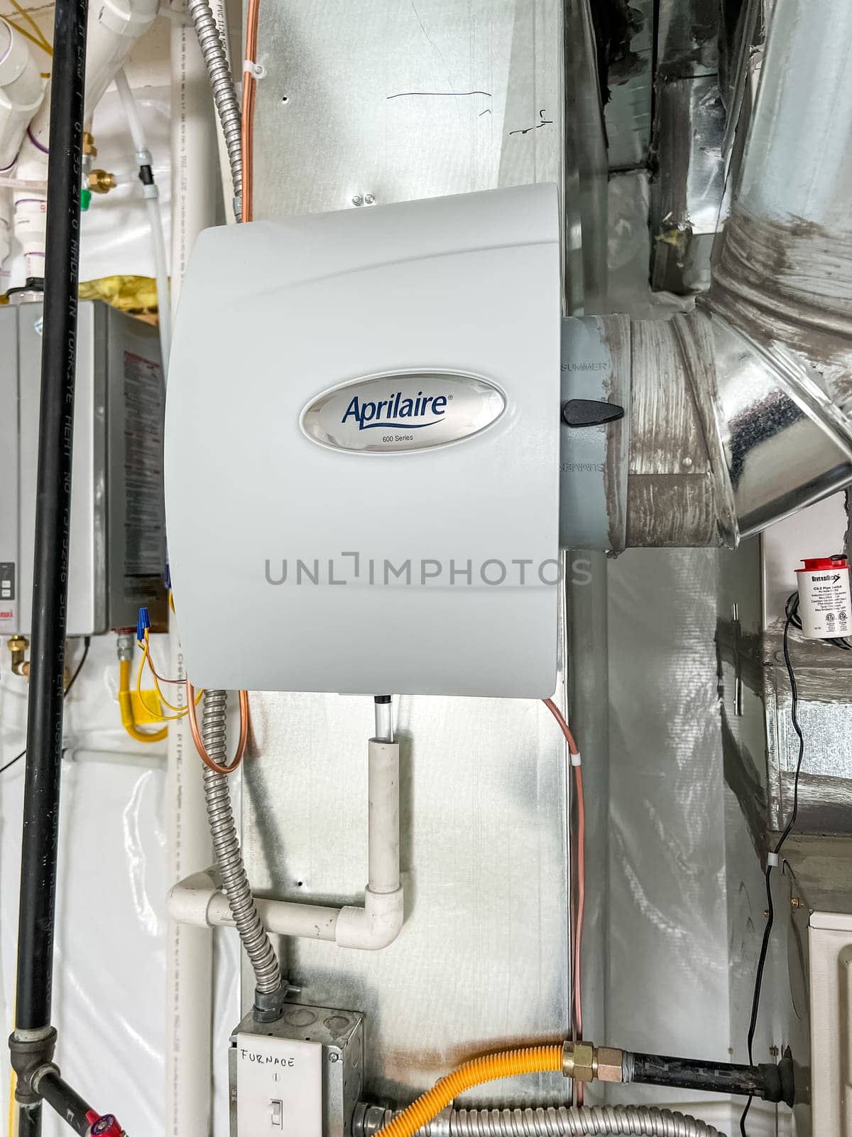 Castle Pines, Colorado USA - January 18, 2023-Aprilaire whole-home humidifier installed on HVAC ductwork in a new residential basement. The unit is connected to pipes and electrical systems, ensuring proper humidity control throughout the house.