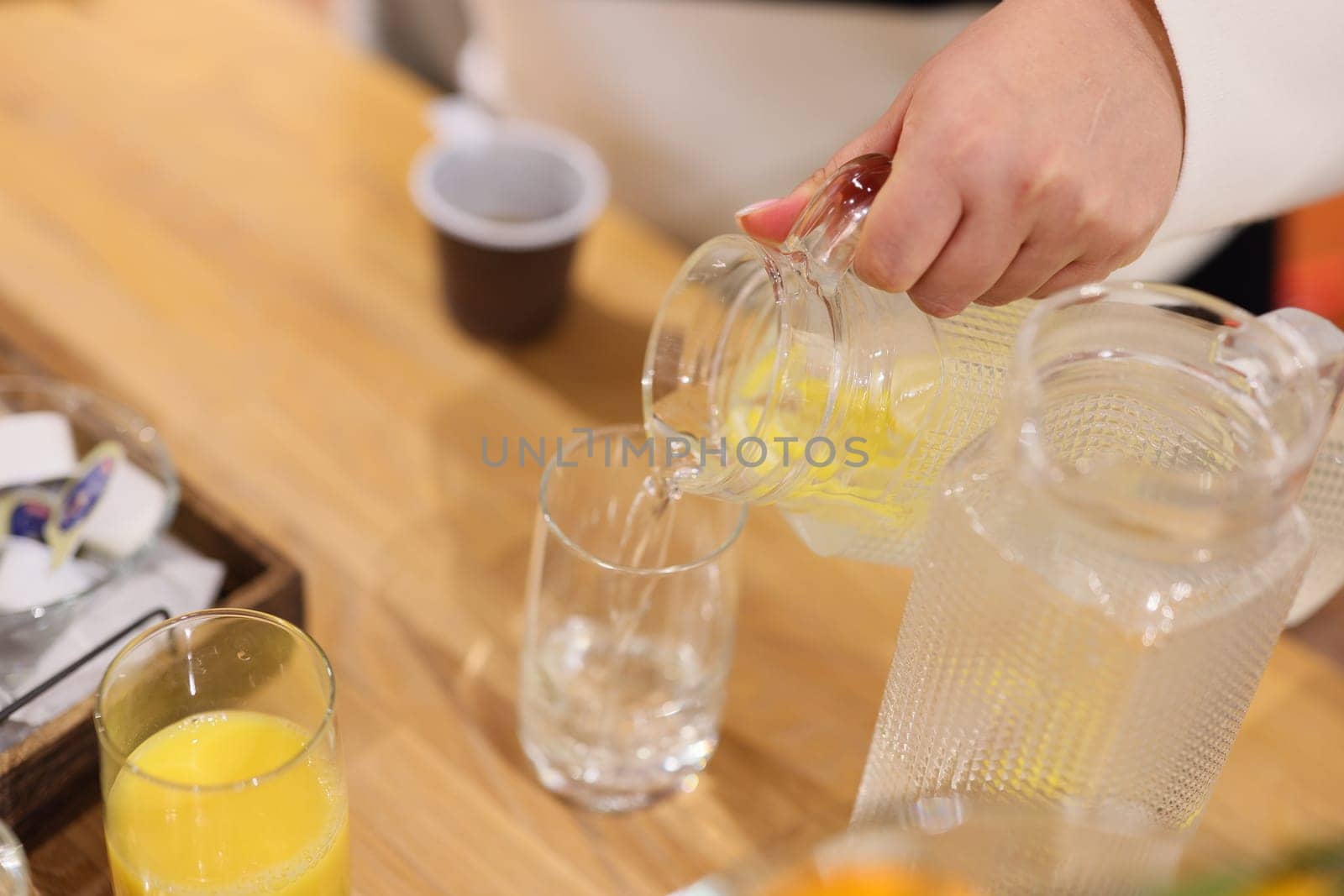 A skilled hand pours a refreshing citrus drink into a glass, showcasing its vibrant colors and enjoyment