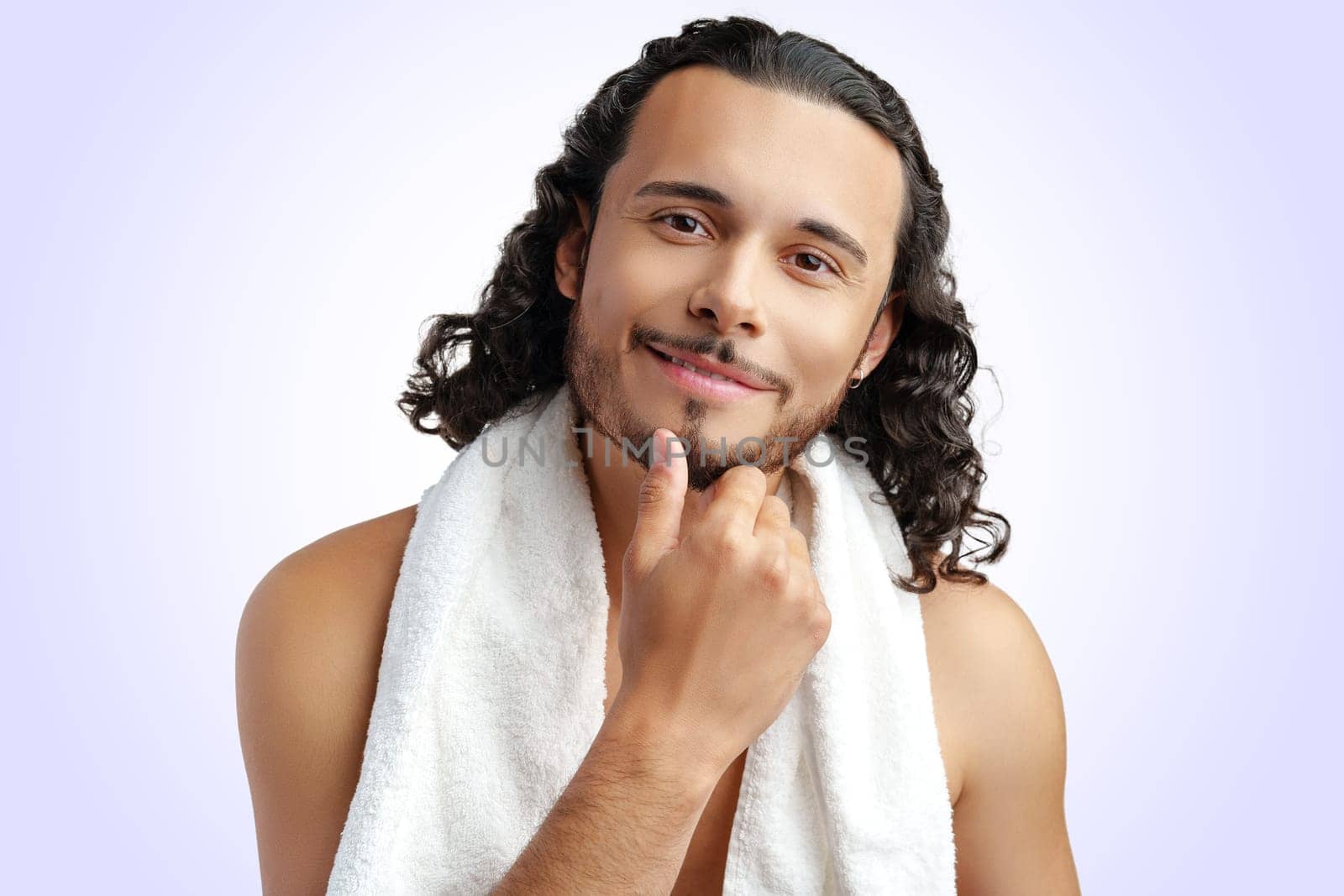 Smiling man with curly hair showing confidence while holding a towel in studio