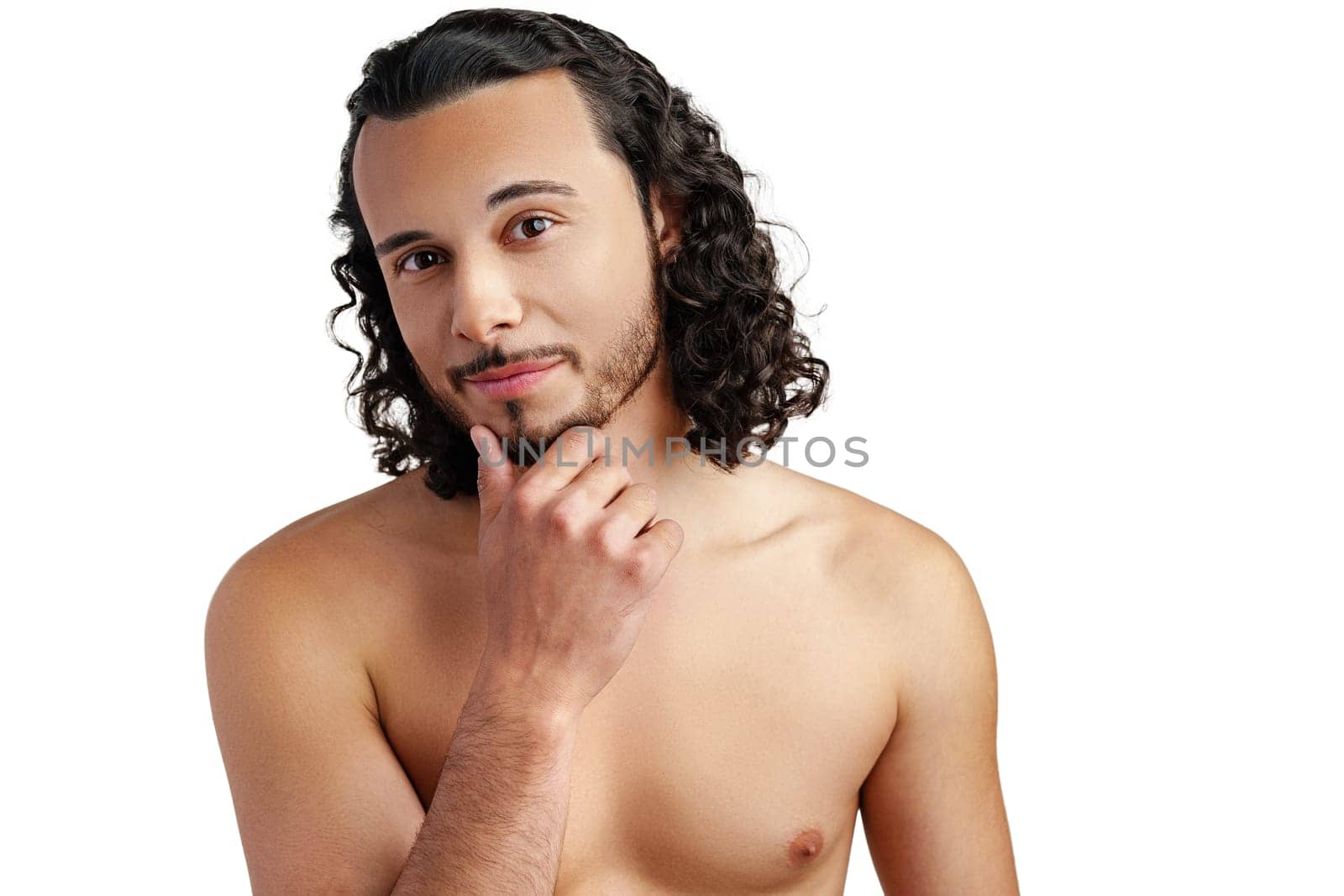 Young man with curly hair thoughtfully posing against a plain background in a studio setting