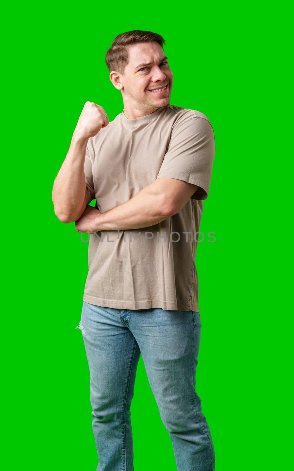 Man celebrating with a confident smile and raised fist against a bright green background in studio