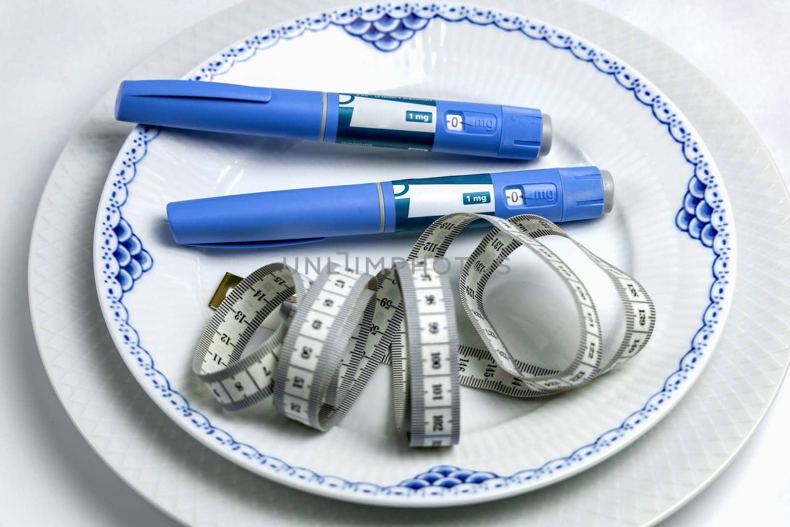 Ozempic Insulin injection pen or insulin cartridge pen for diabetics on a white plate. Medical equipment for diabetes parients.