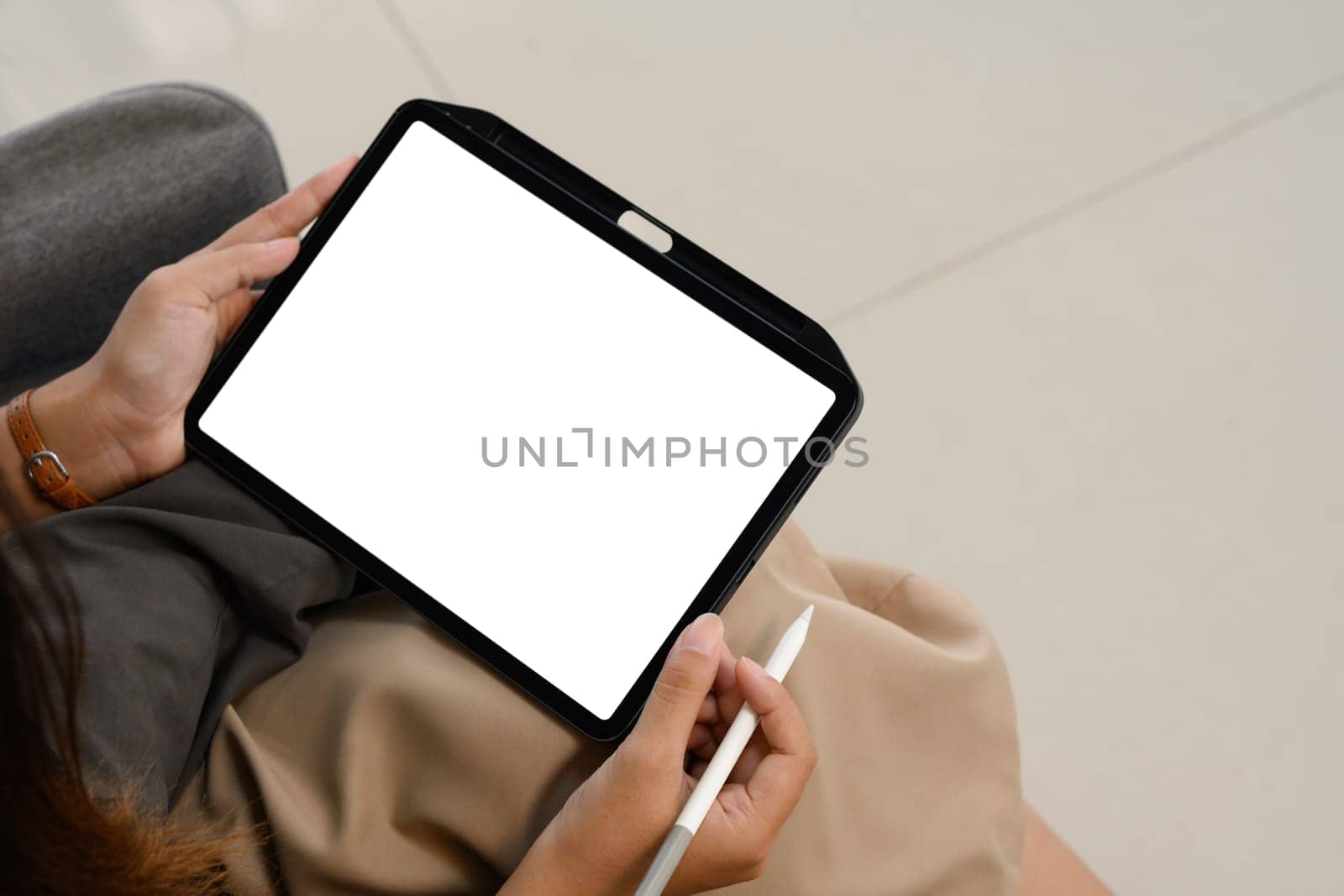 Cropped image of a woman holding digital tablet with blank desktop screen sitting on sofa.