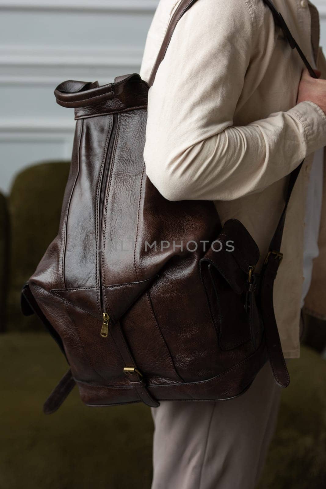 A man in a beige shirt posing with a brown backpack