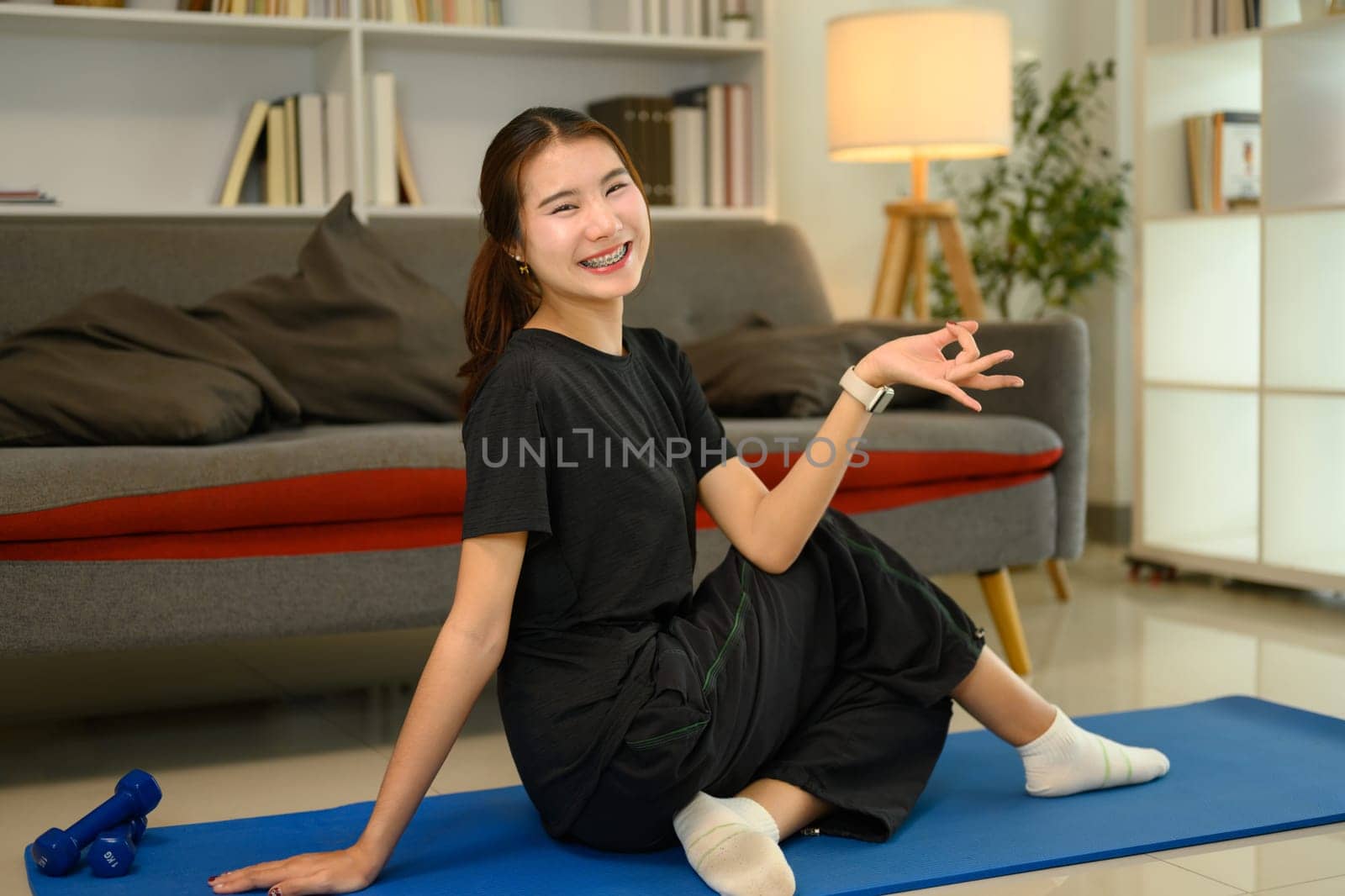 Smiling young woman practicing yoga at home. Balanced and active lifestyle concept.