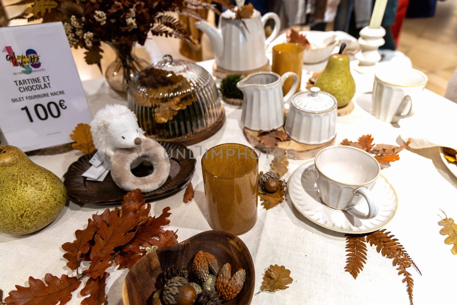Autumn table setting with white cups and yellow oak leaves on the table. Paris, France - Oktober 25, 2024