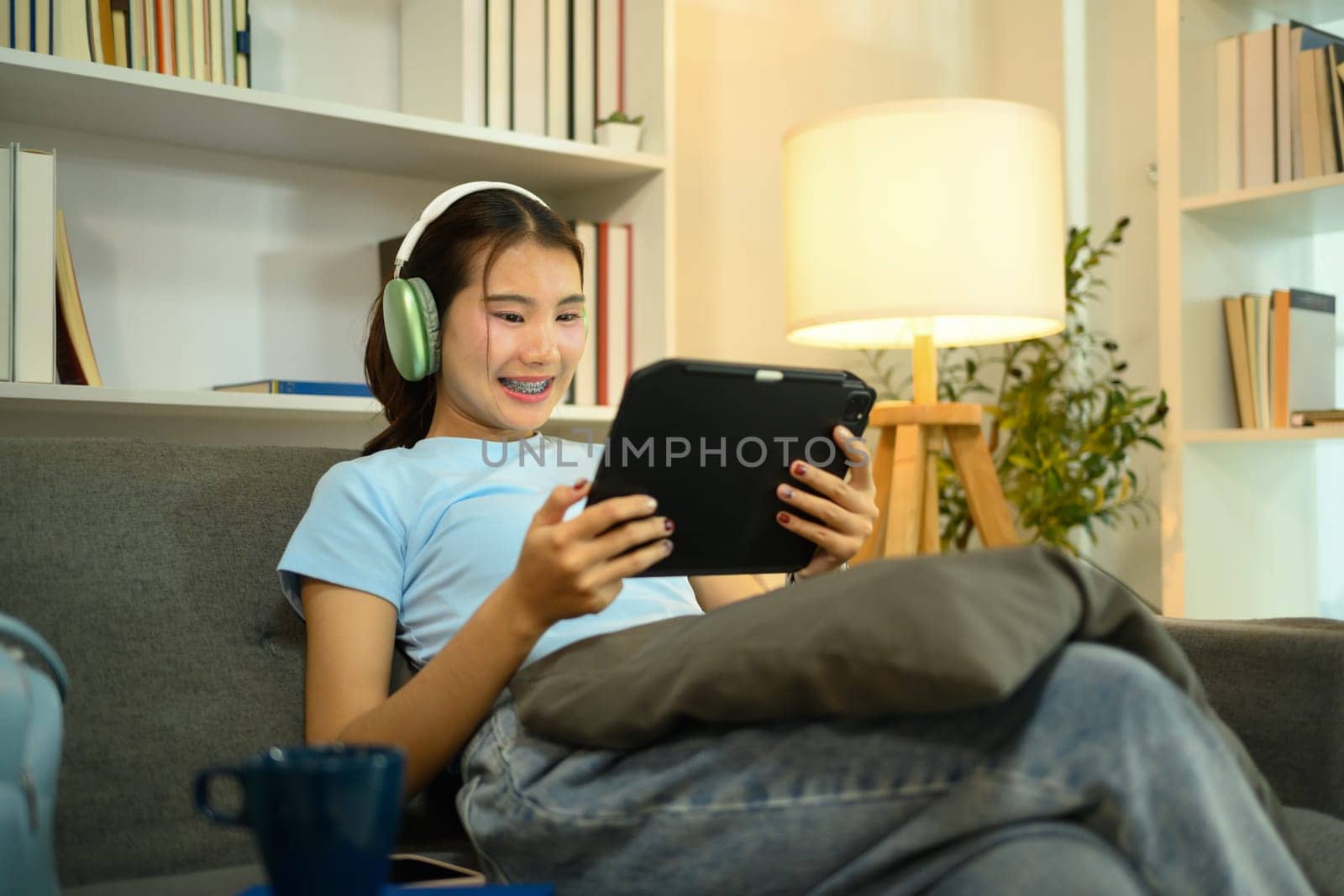 Pretty young woman with headphones enjoying content on digital tablet.