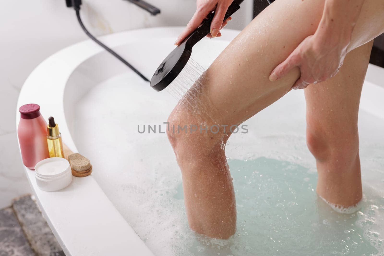 Unrecognizable woman washes the foam off her feet in the shower,