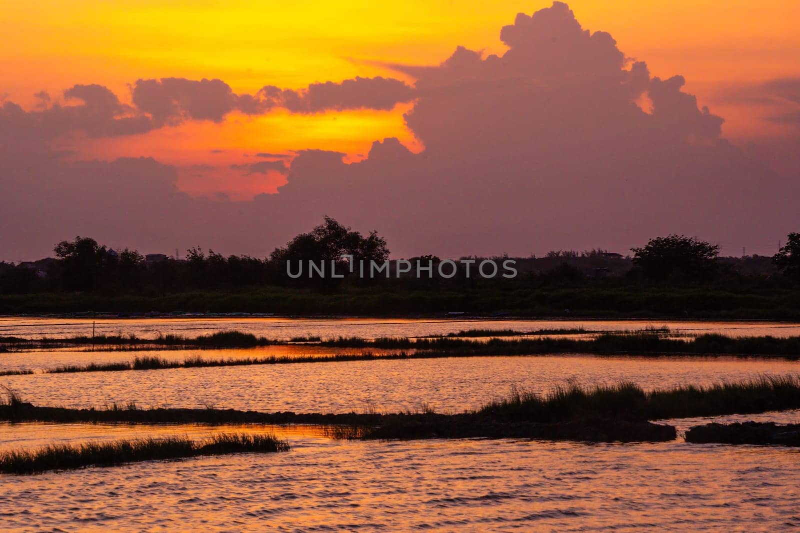 A dramatic sky and silhouetted figures create a stunning scene at sunset.