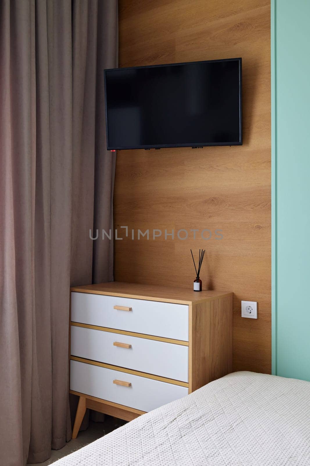 This stylish and modern bedroom boasts a wallmounted television, elegant curtains, and chic contemporary furnishings
