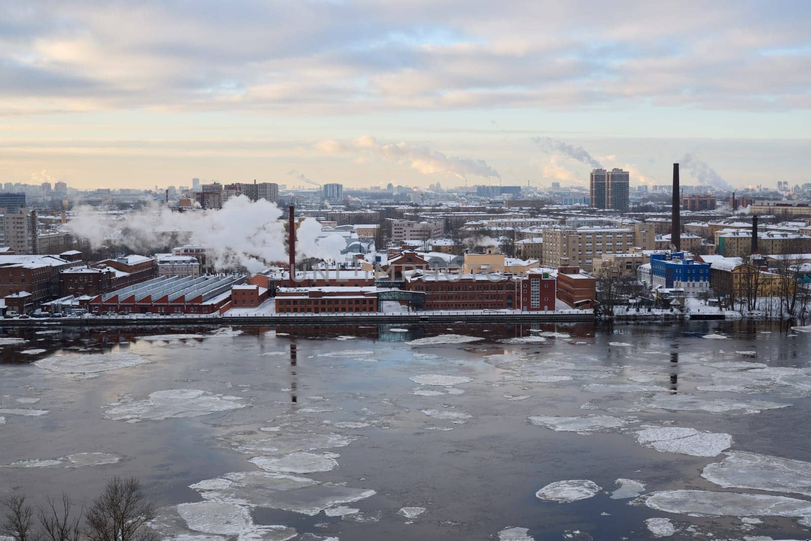 A captivating and stunning winter view featuring an industrial area beautifully reflecting on a river with floating ice