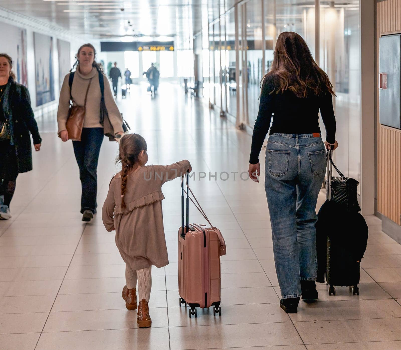 Woman with little girl and suitcases at the airport. Copenhagen, Denmark - December 12, 2024