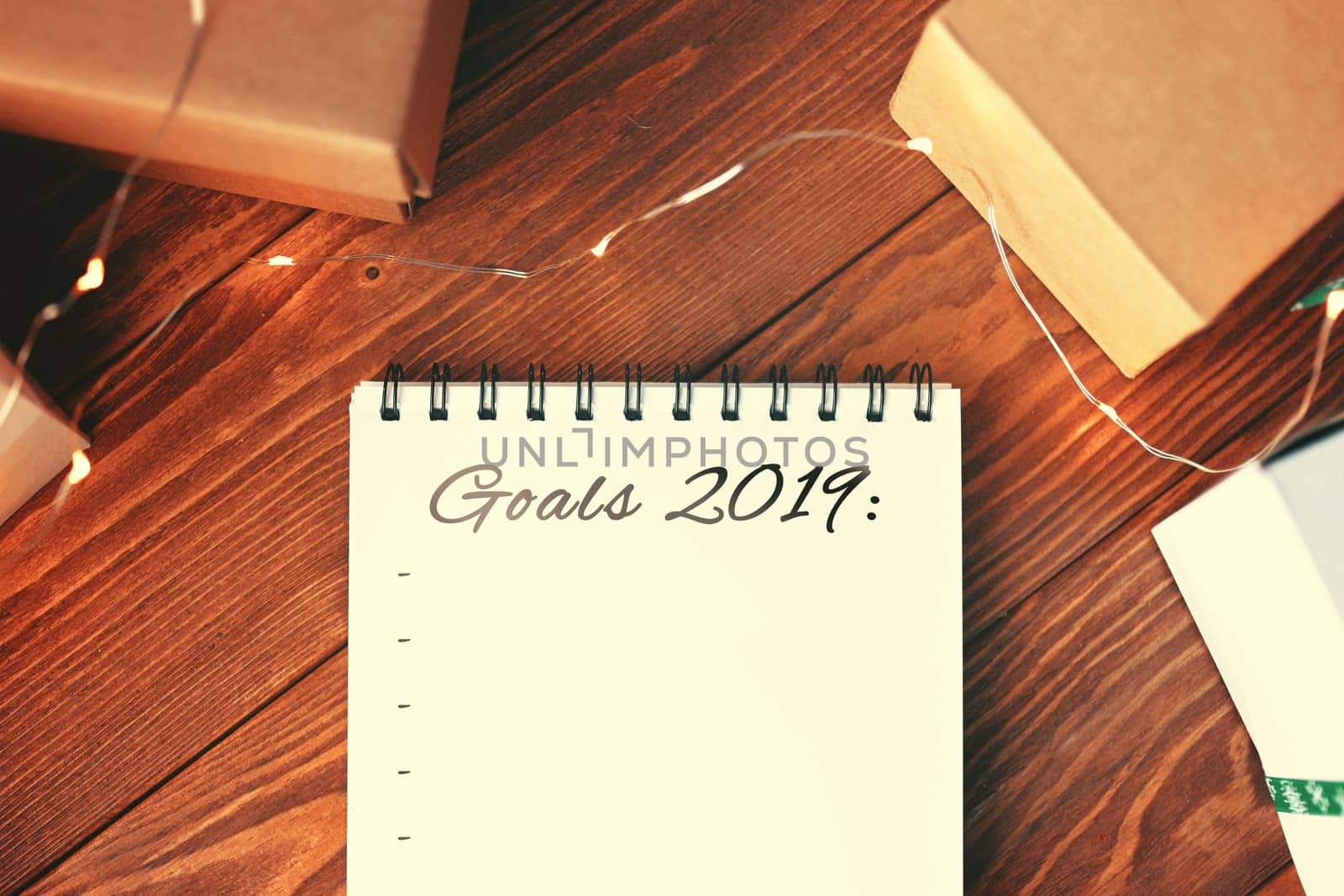 Prepare for Christmas with Notepad and gifts. Notebook with the words Goals 2019 lies on a wooden table. Close up.