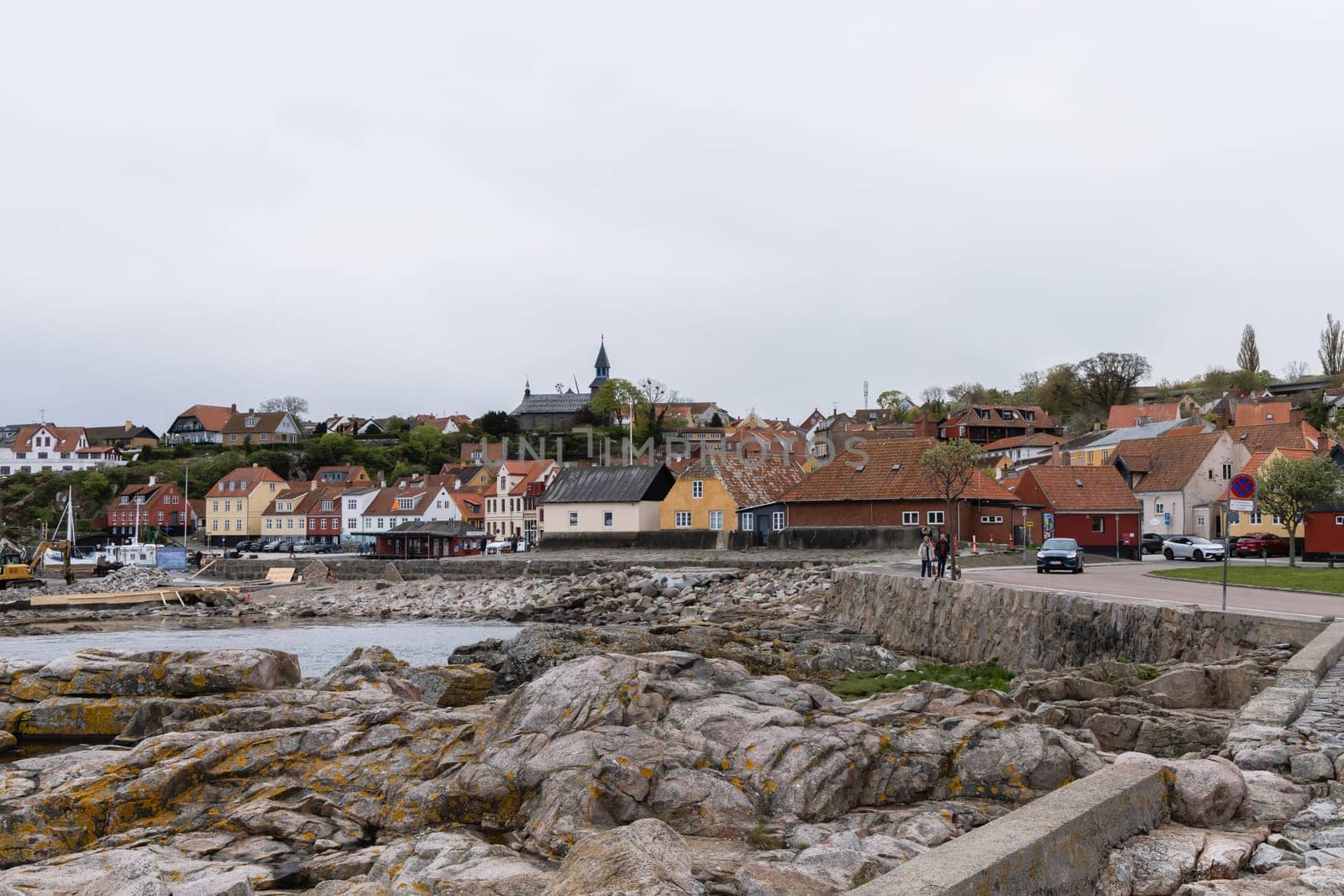 Rocky seashore and a small town in the distance in cloudy weather. Beautiful landscape. Bornholm, Denmark - December 4, 2024
