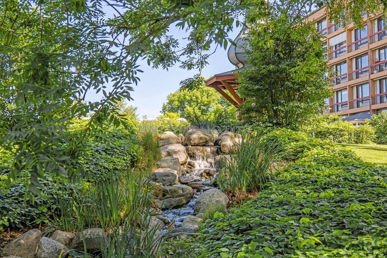 A small waterfall among large stones and green trees. High quality photo