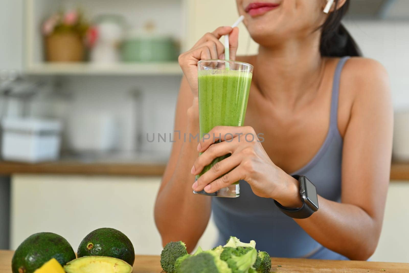 Happy young asian woman enjoying green smoothie to refresh after workout. Healthy lifestyle and diet concept by prathanchorruangsak