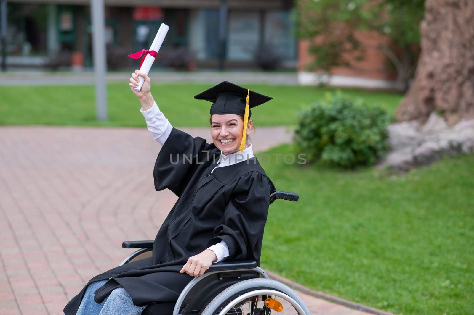 Happy caucasian woman in a wheelchair holding her diploma outdoors. by mrwed54