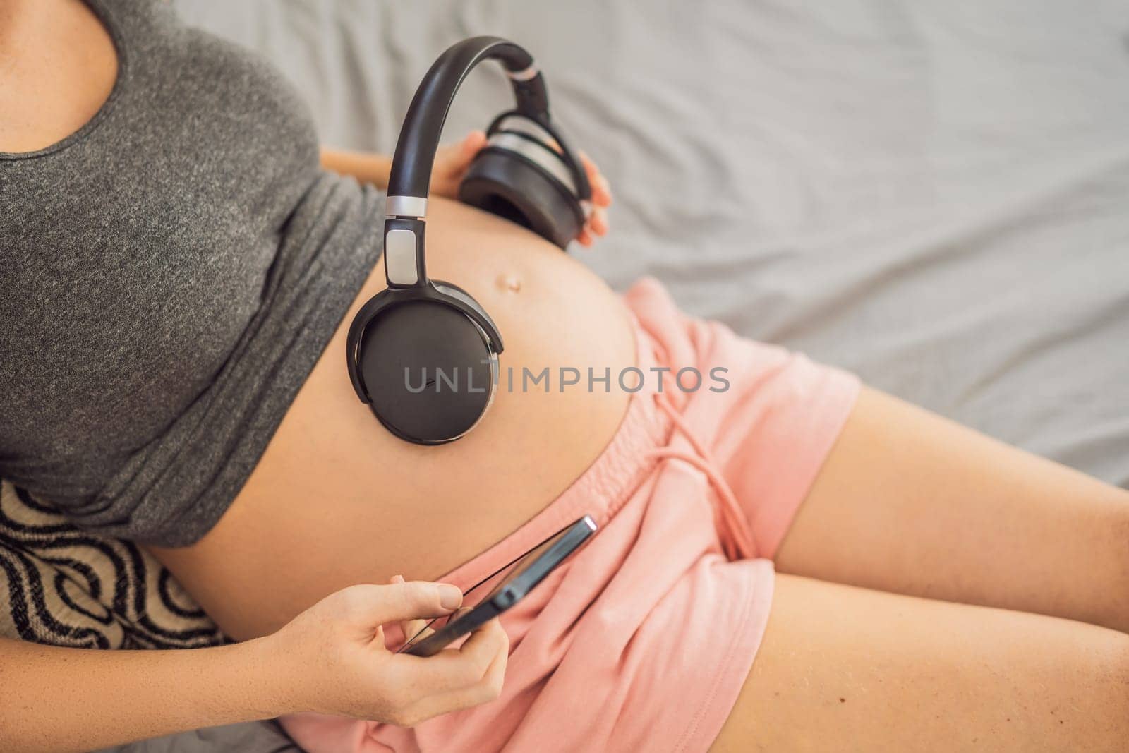 Melodies in the womb: Headphones placed on a pregnant belly, bonding through music, a heartwarming connection between mother and baby.