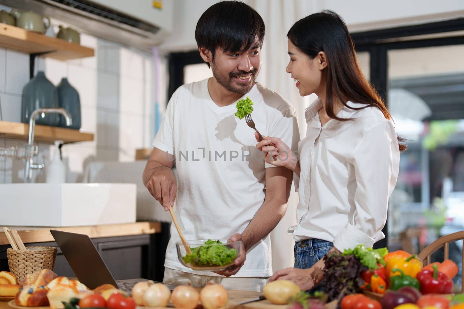 Couple making food or salad in the kitchen at home. by Manastrong
