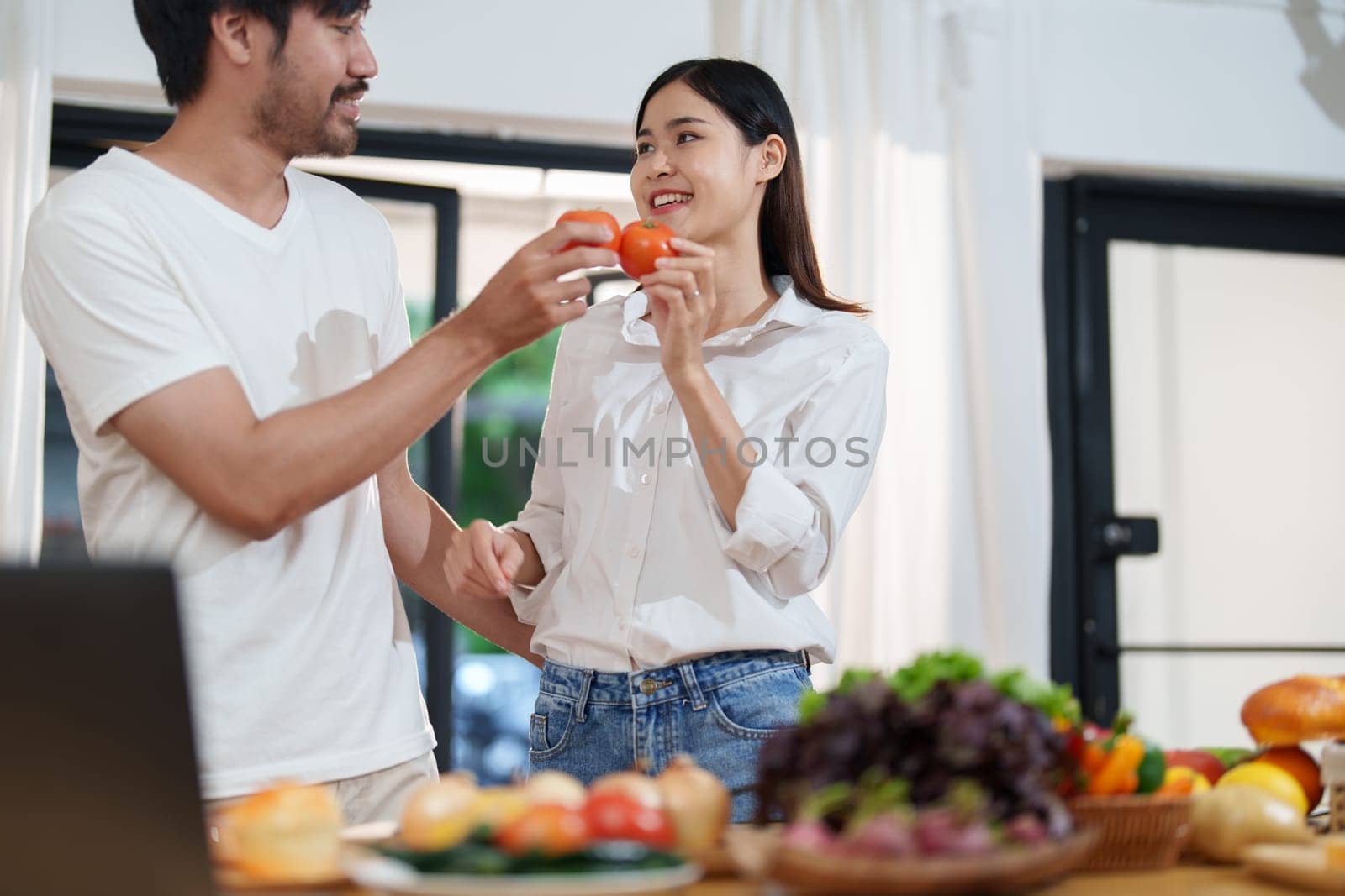 Couple cutting tomatoes for cooking or salad in home kitchen by Manastrong