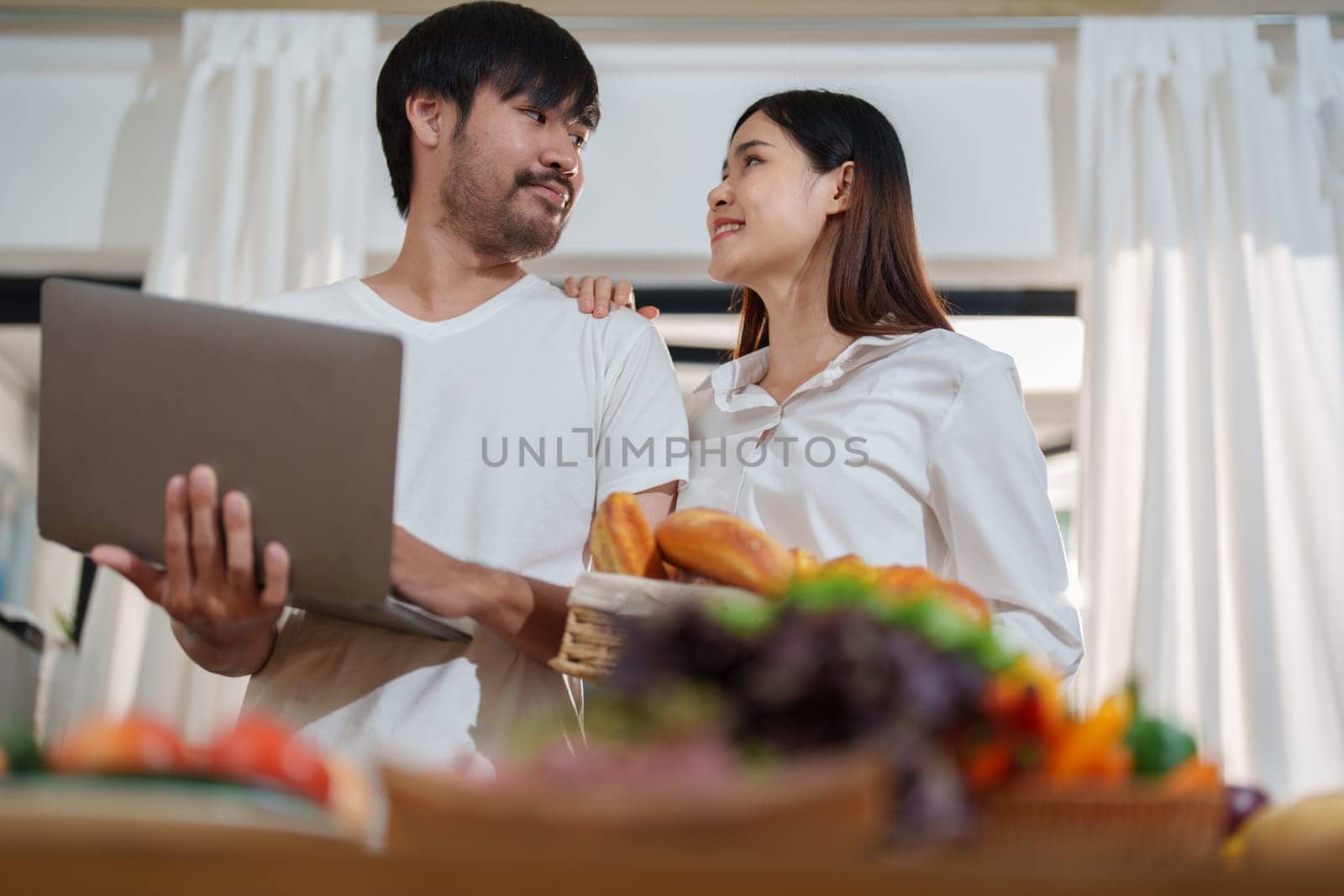 Couple making food or salad in the kitchen at home. by Manastrong