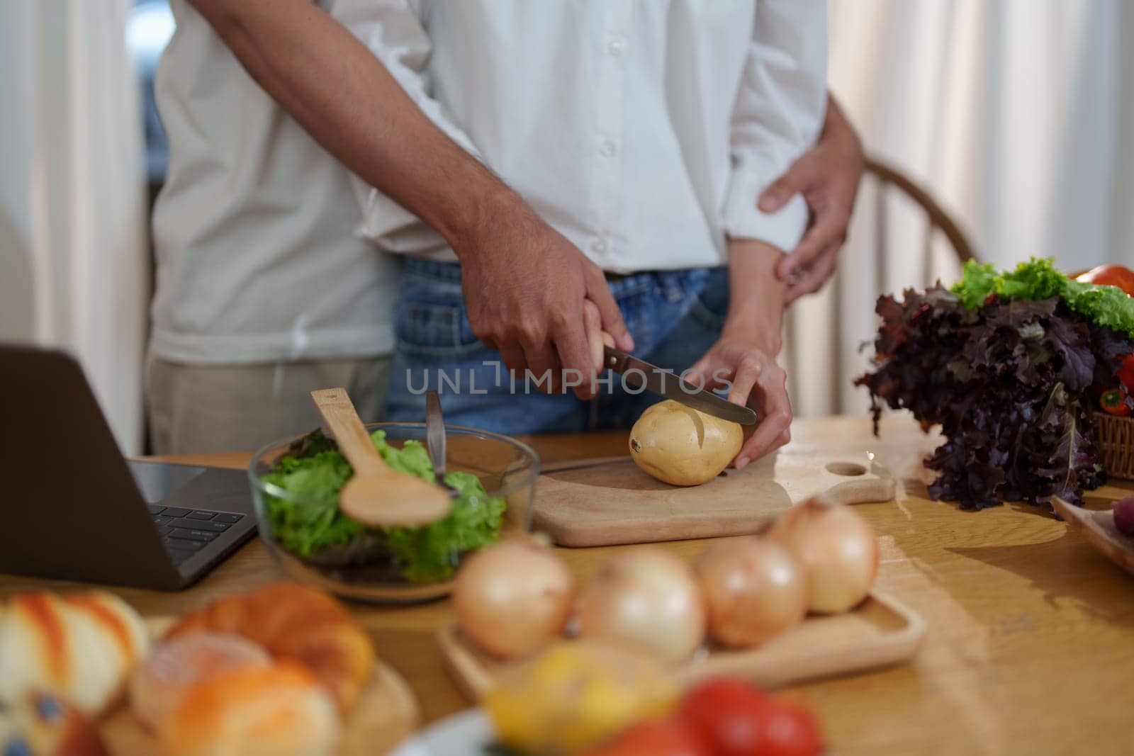 Couple cutting potatoes to cook or make salad in home kitchen. by Manastrong