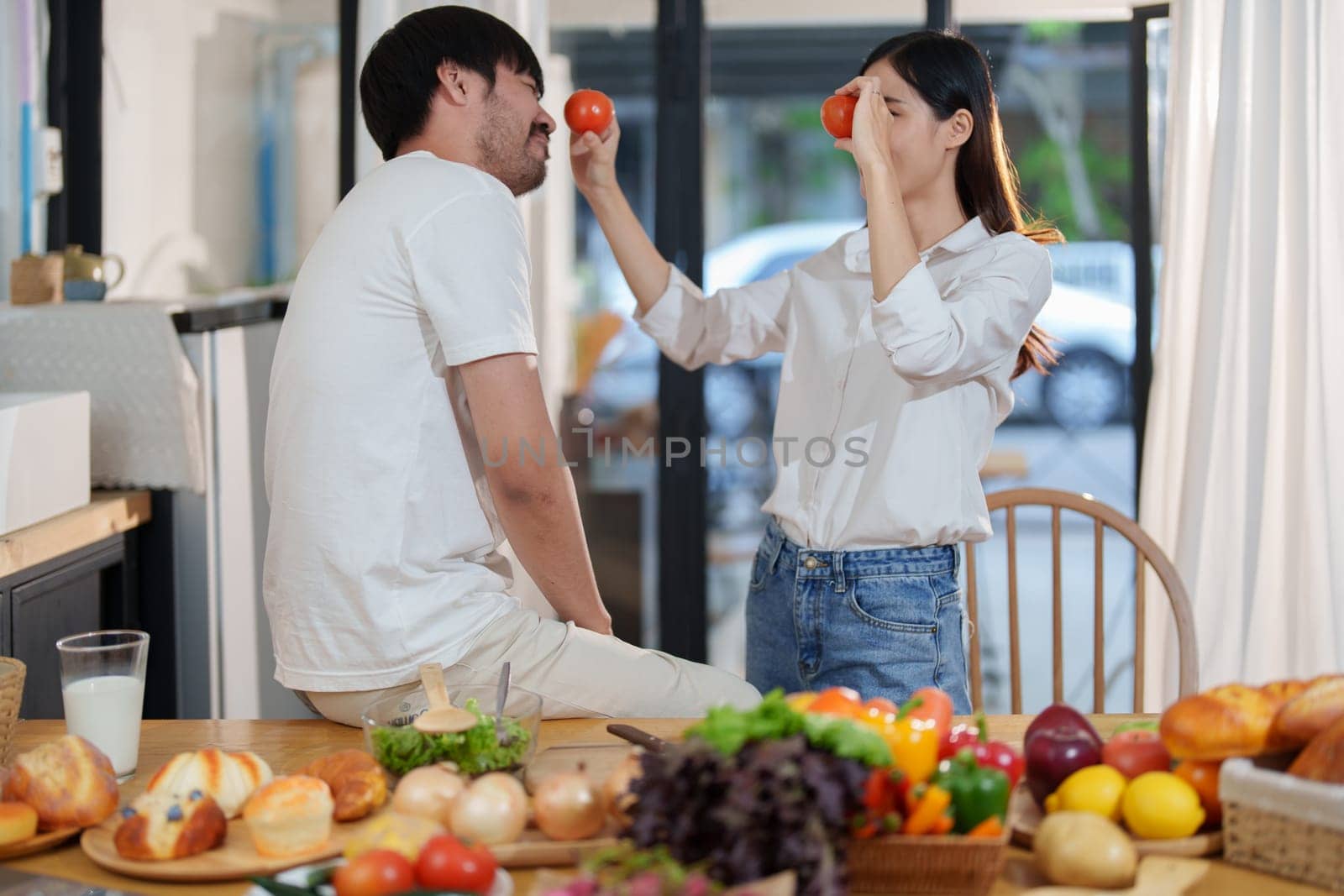 Couple cutting tomatoes for cooking or salad in home kitchen by Manastrong