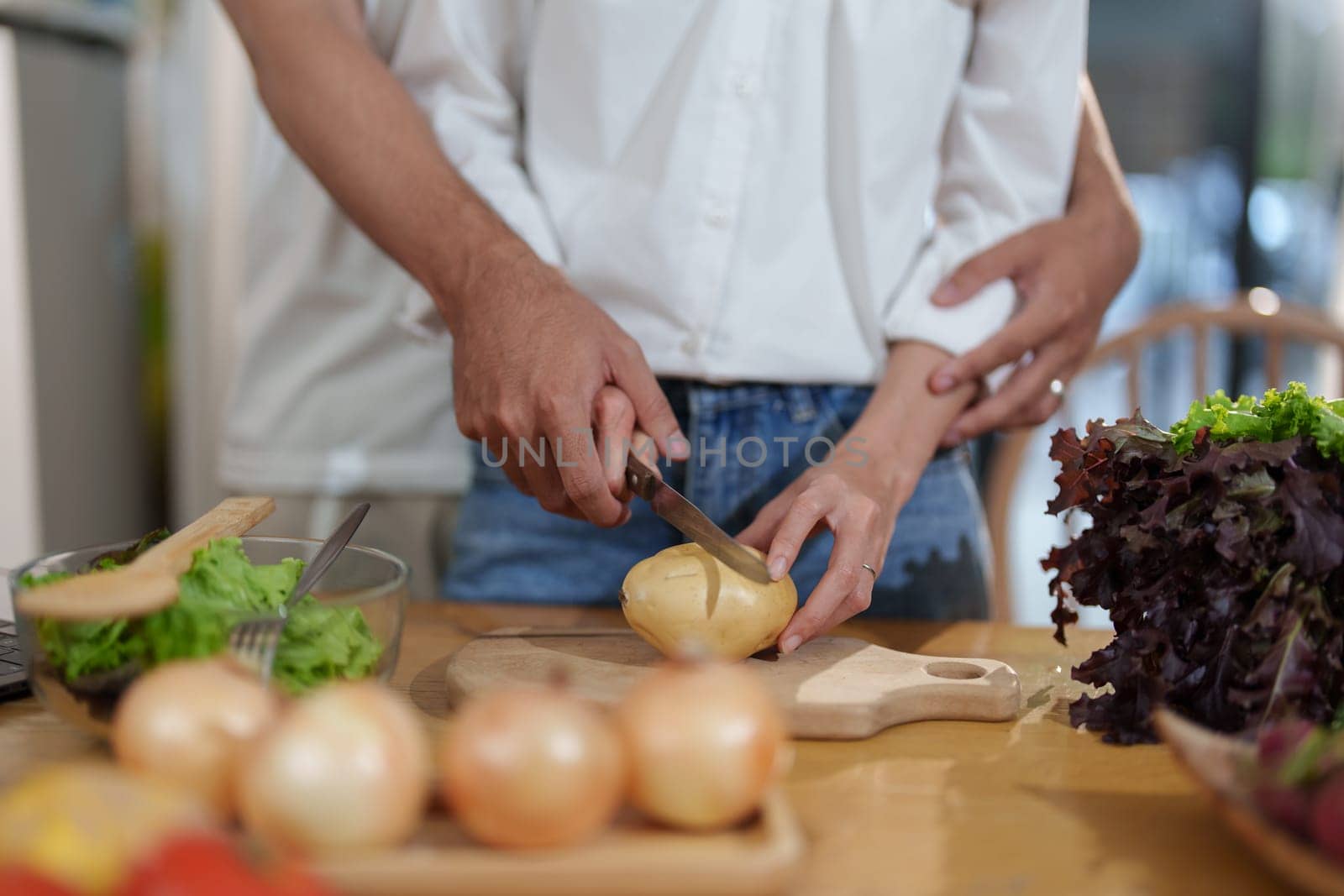 Couple cutting potatoes to cook or make salad in home kitchen. by Manastrong