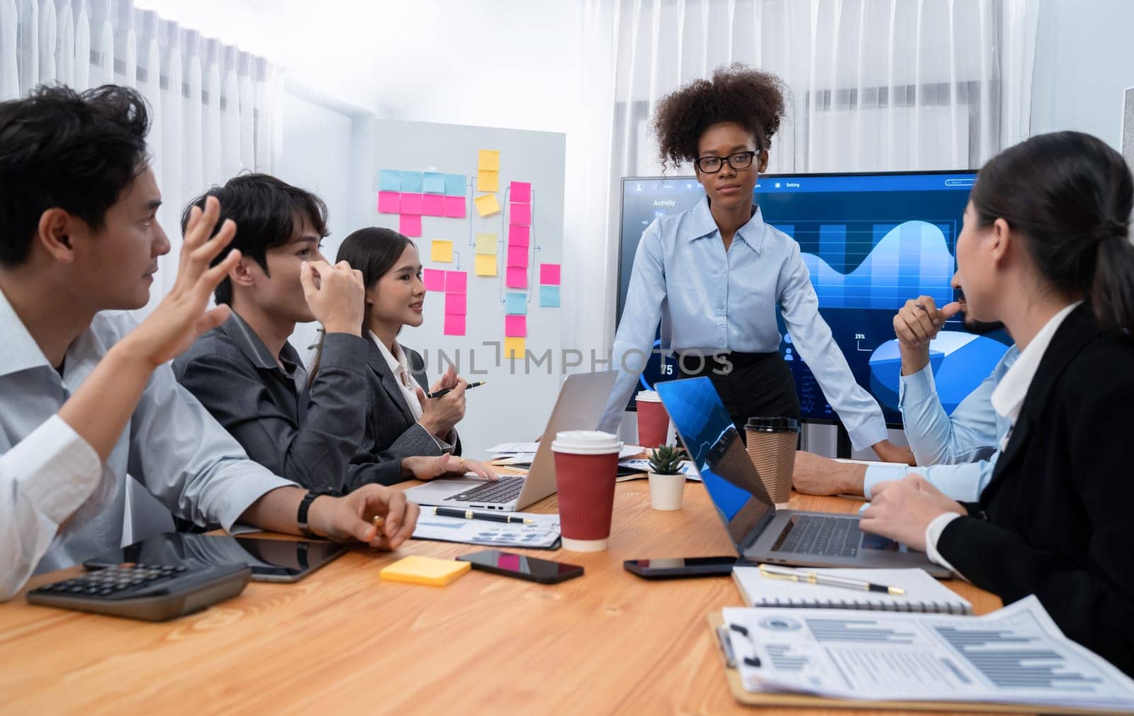 Young african businesswoman presenting data analysis dashboard on TV screen in modern meeting. Business presentation with group of business people in conference room. Concord