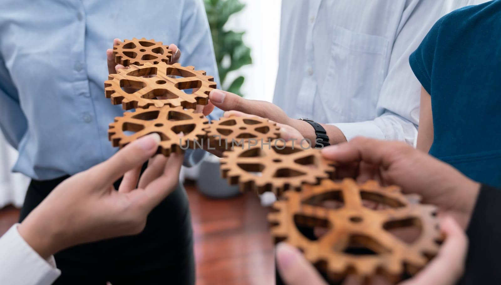 Office worker holding cog wheel as unity and teamwork in corporate workplace concept. Diverse colleague business people showing symbol of visionary system and mechanism for business success. Concord