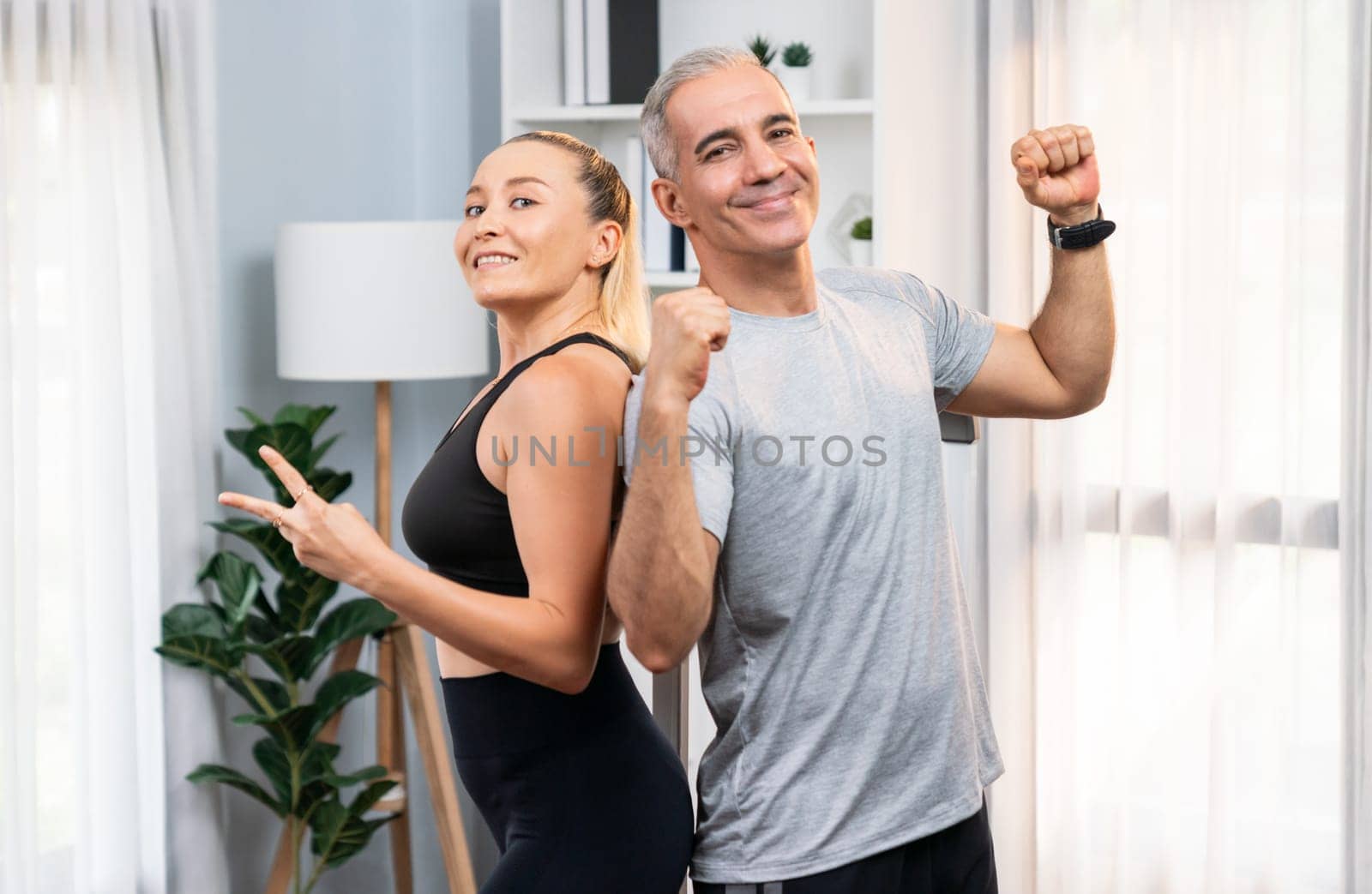 Athletic and sporty senior couple portrait in sportswear with successful or celebrating after overcome struggle posture as home exercise concept with healthy fit body lifestyle after retirement. Clout