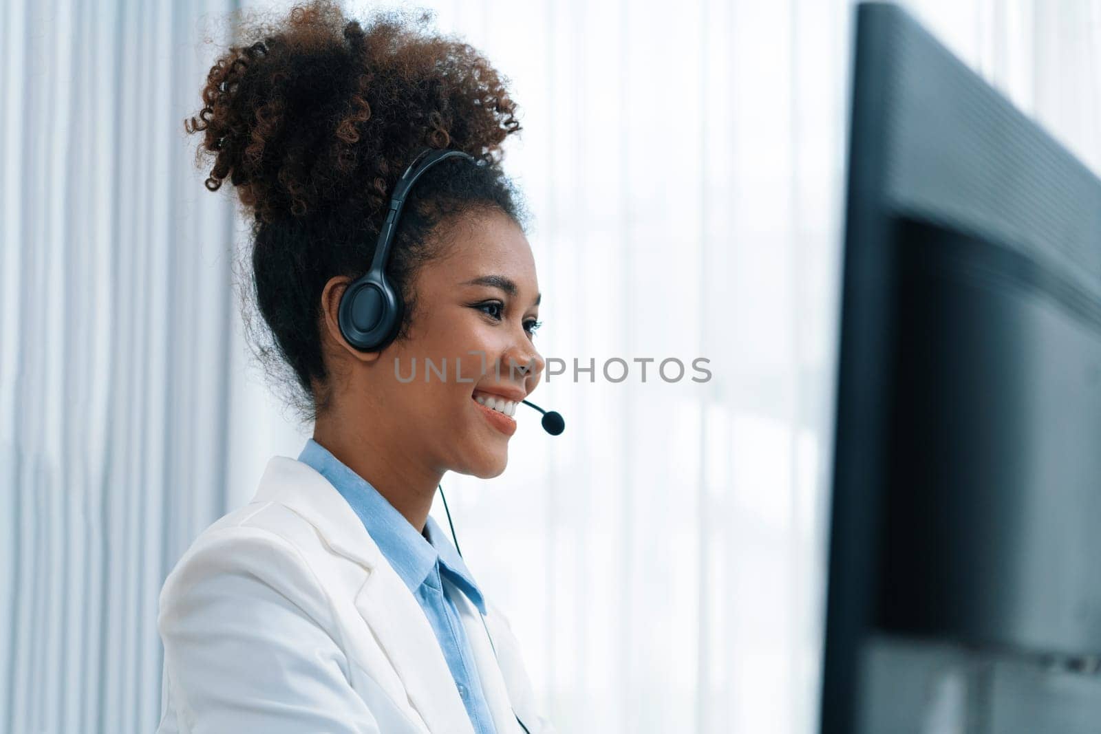 African American young businesswoman wearing headset working in crucial office by biancoblue