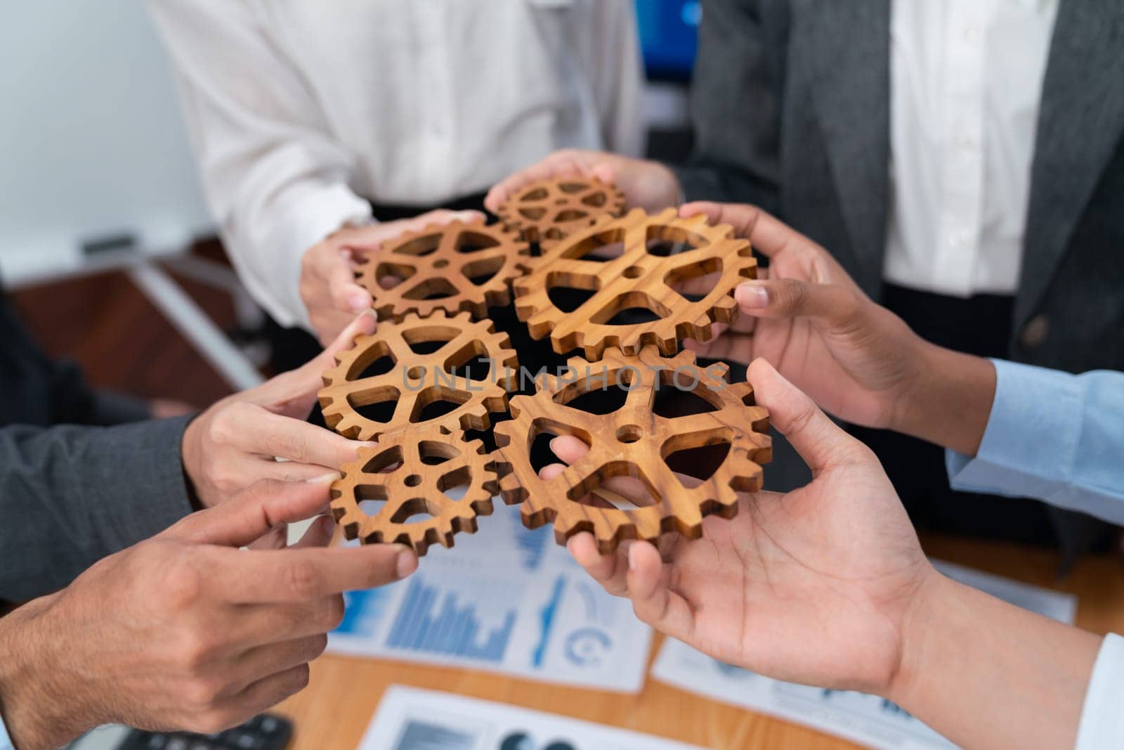 Office worker holding cog wheel as unity and system teamwork in corporate workplace with piles of business paper and financial report on meeting table. Business people with business success. Concord