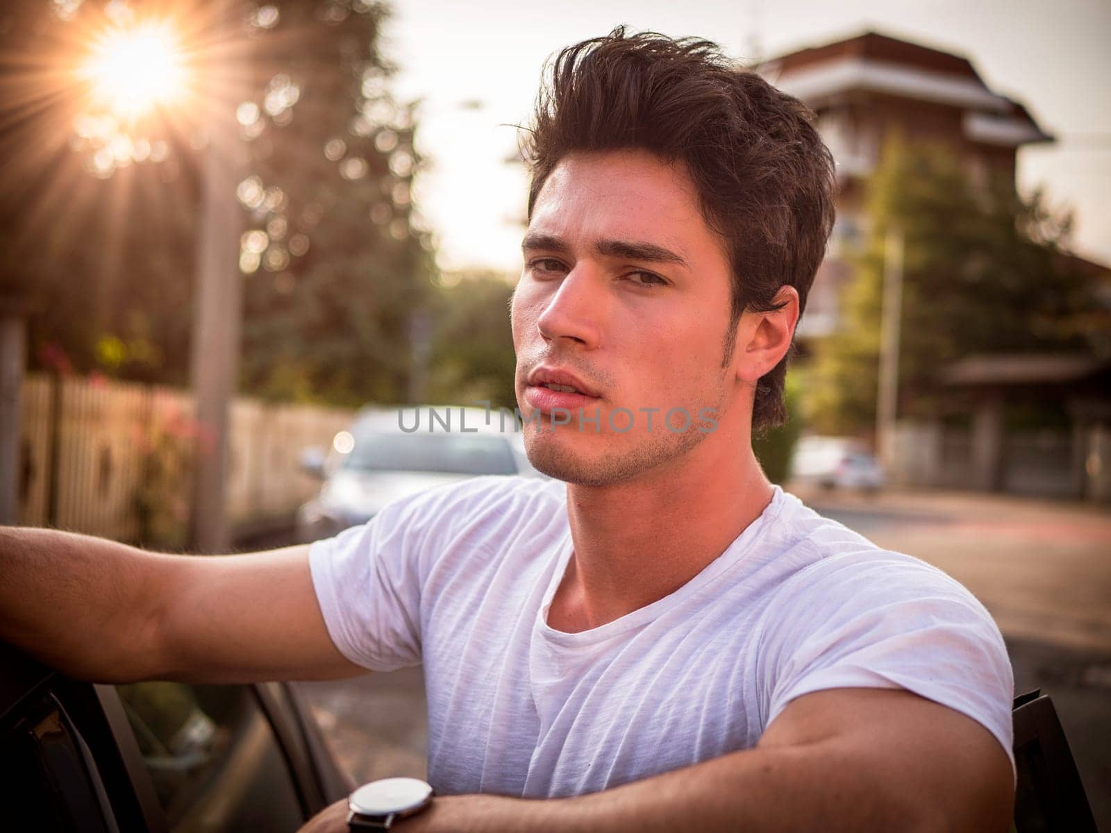 A man in a white shirt leaning out of a car window