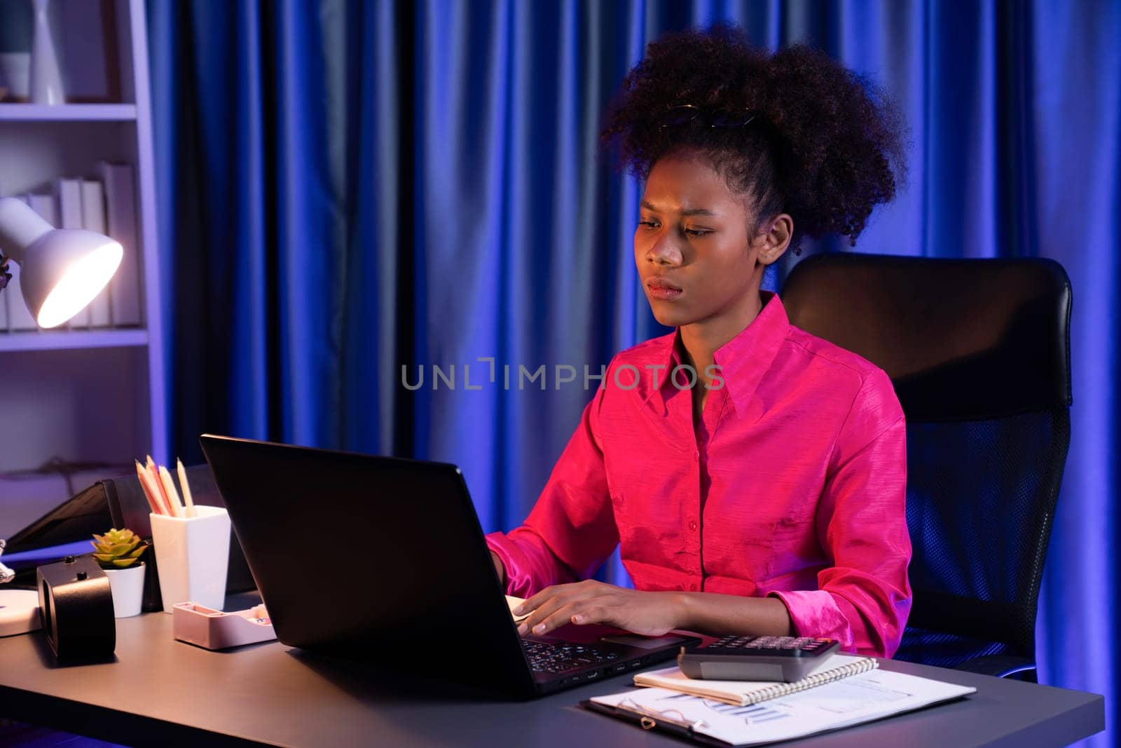 African woman businesswoman or blogger wearing pink shirt with serious face, looking and focusing on screen laptop with struggle project. Concept of stressful expression at work from home. Tastemaker.