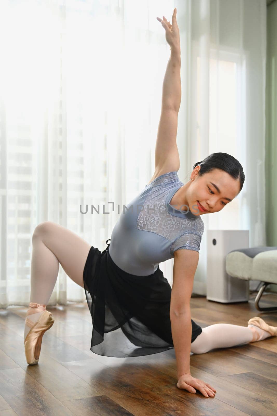 Dedicated young asian woman practicing ballet in bright living room. Dance, art, education and flexibility concept.