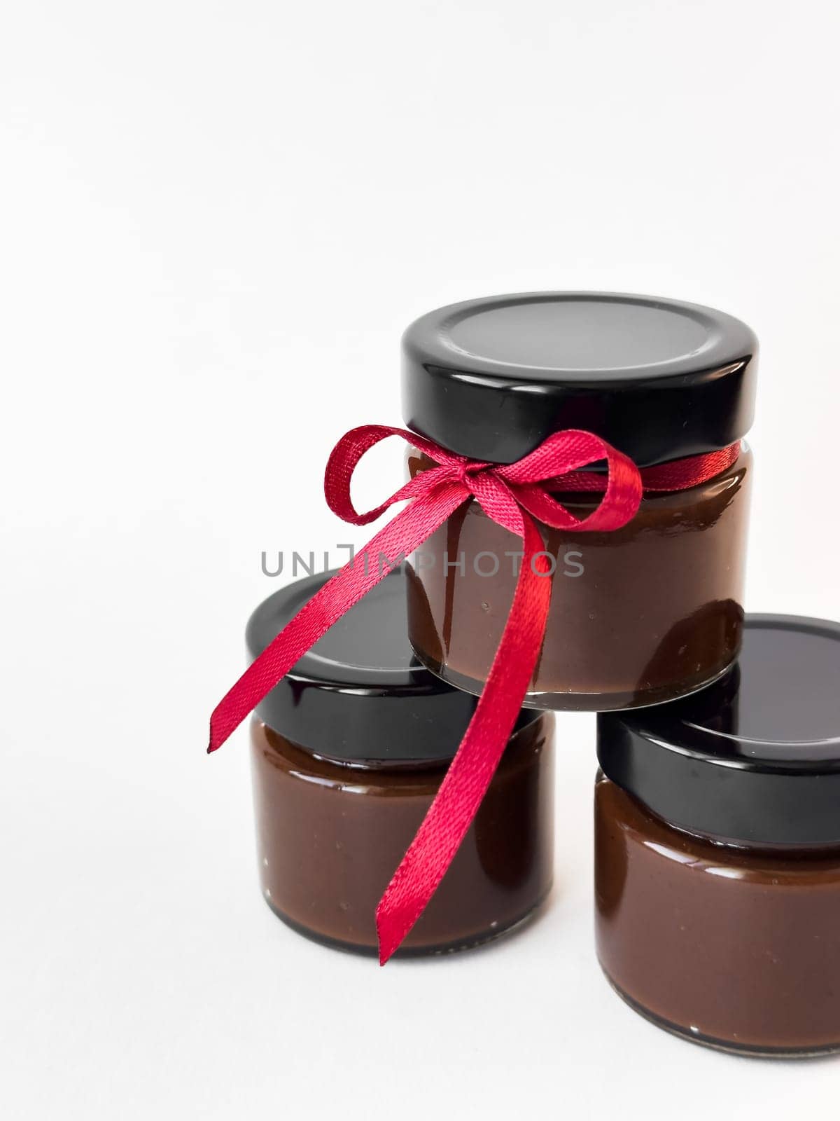 Luxurious chocolate spread jars with red ribbon tied for gift giving elegance.