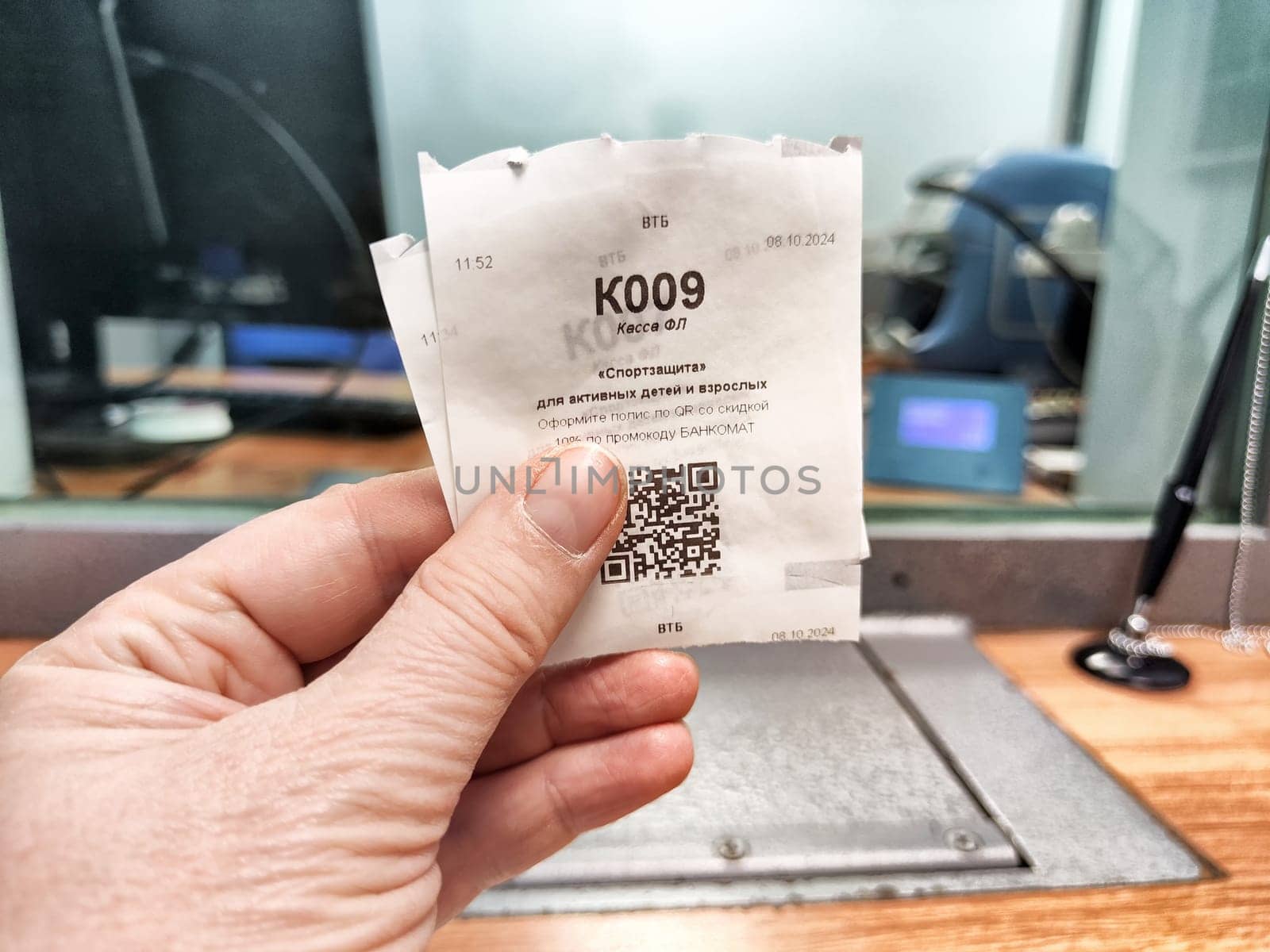 Kirov, Russia - October 08, 2024: A hand holds a ticket displaying a queue number, indicating a visit to the bank for service during business hours.