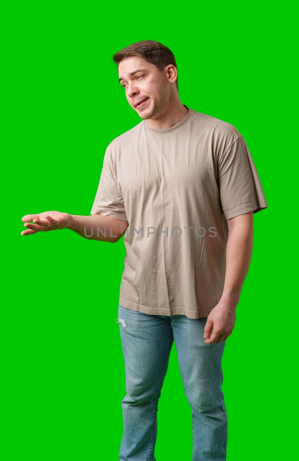 Man with a confused expression gestures with his hands against a bright green background in studio