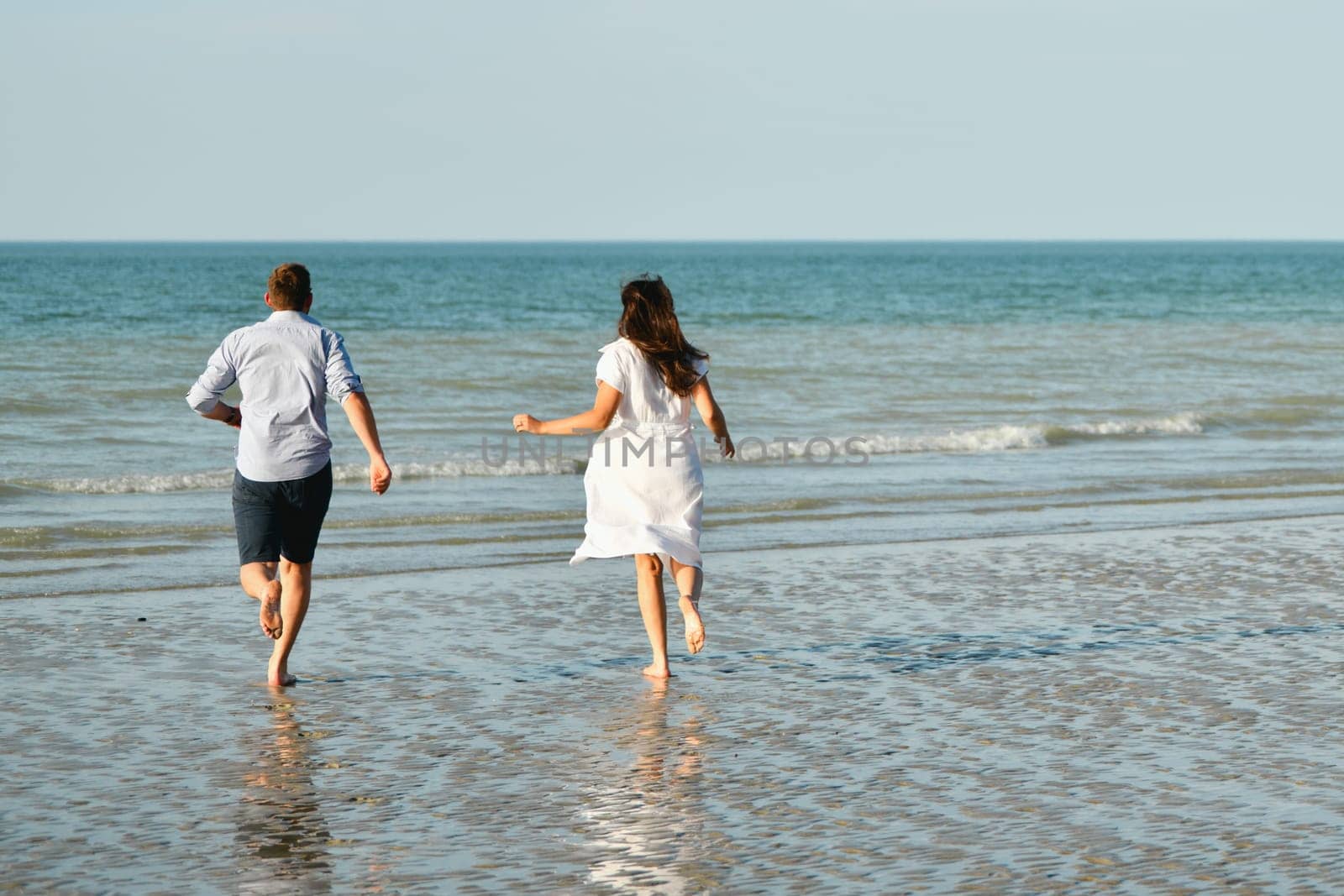 Back view of a couple running on the Atlantic ocean