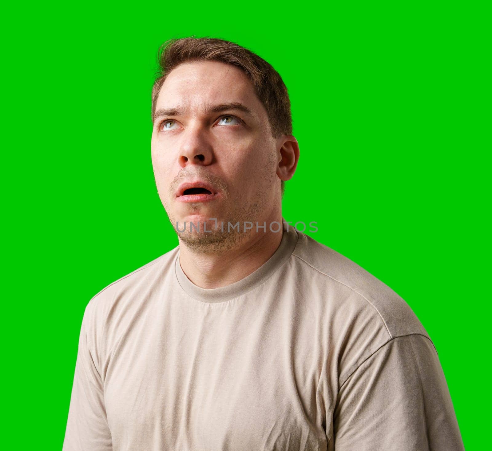 Man making a humorous expression against a bright green background in studio
