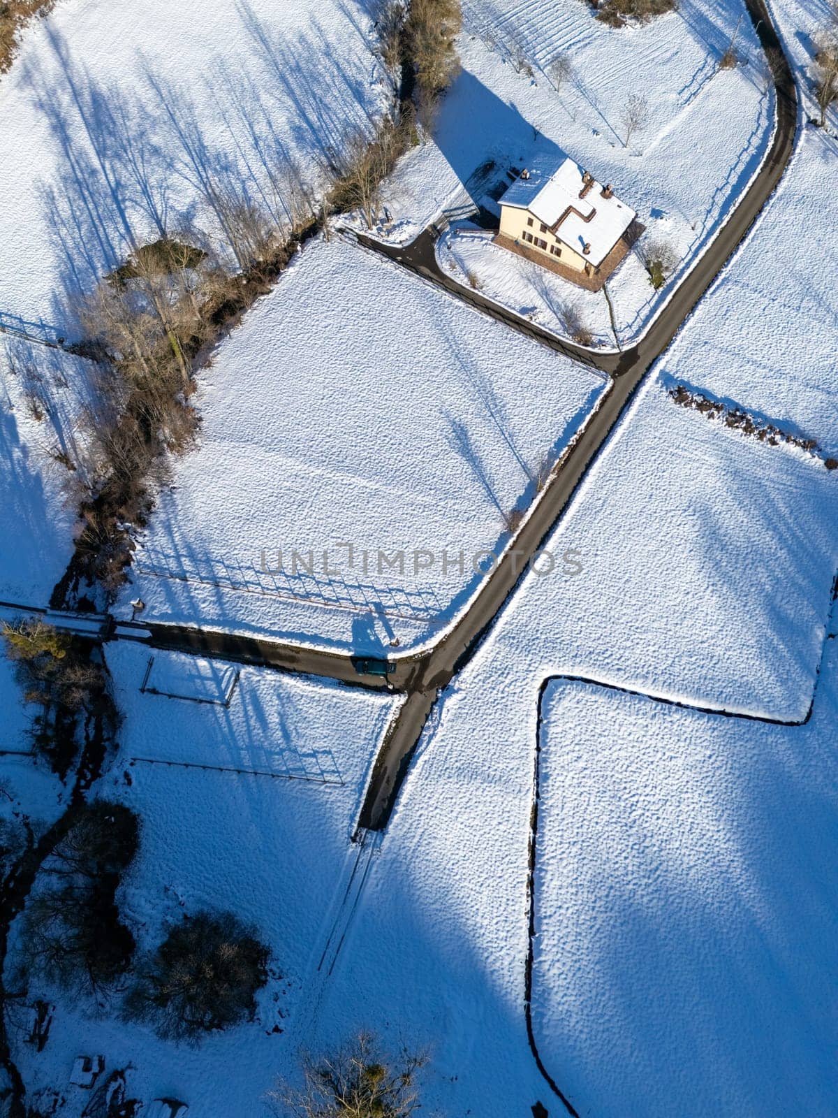 Aerial view of Monte Lama area in Rocchetta, Morfasso, Italy, featuring a snowy landscape with a house and intersecting roads